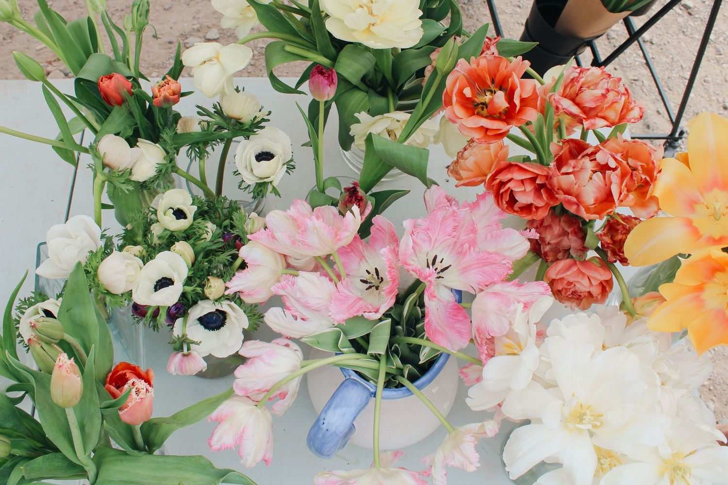 Colorful spring flower arrangement with pink tulips, white anemones, and orange blooms displayed on a light surface.