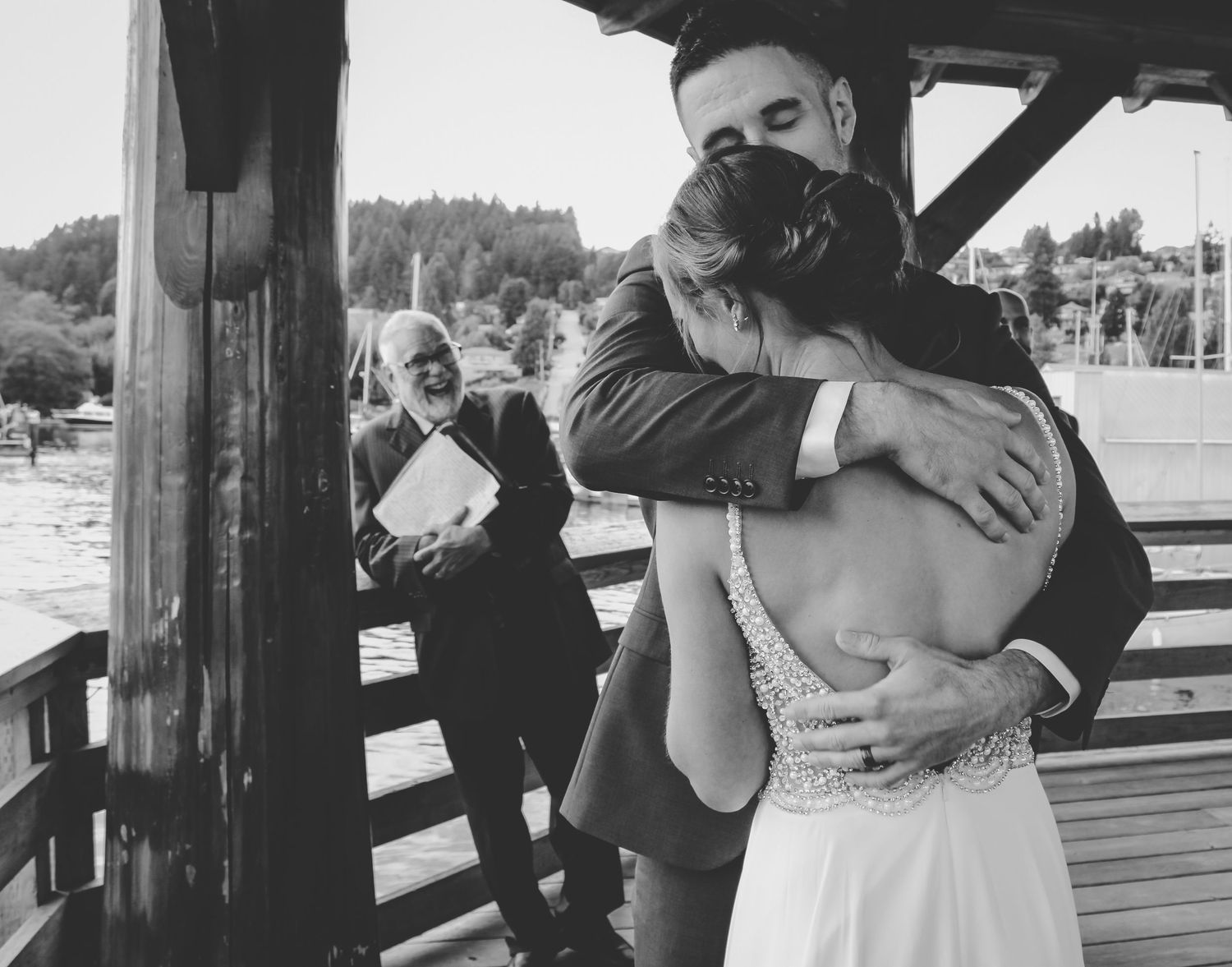 Black and white romantic moment captured on a wooden dock by the water.