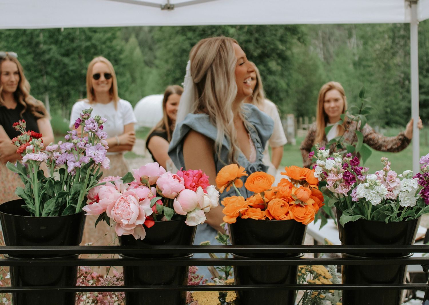 Display of colorful flowers including pink peonies and orange blooms at an outdoor market.