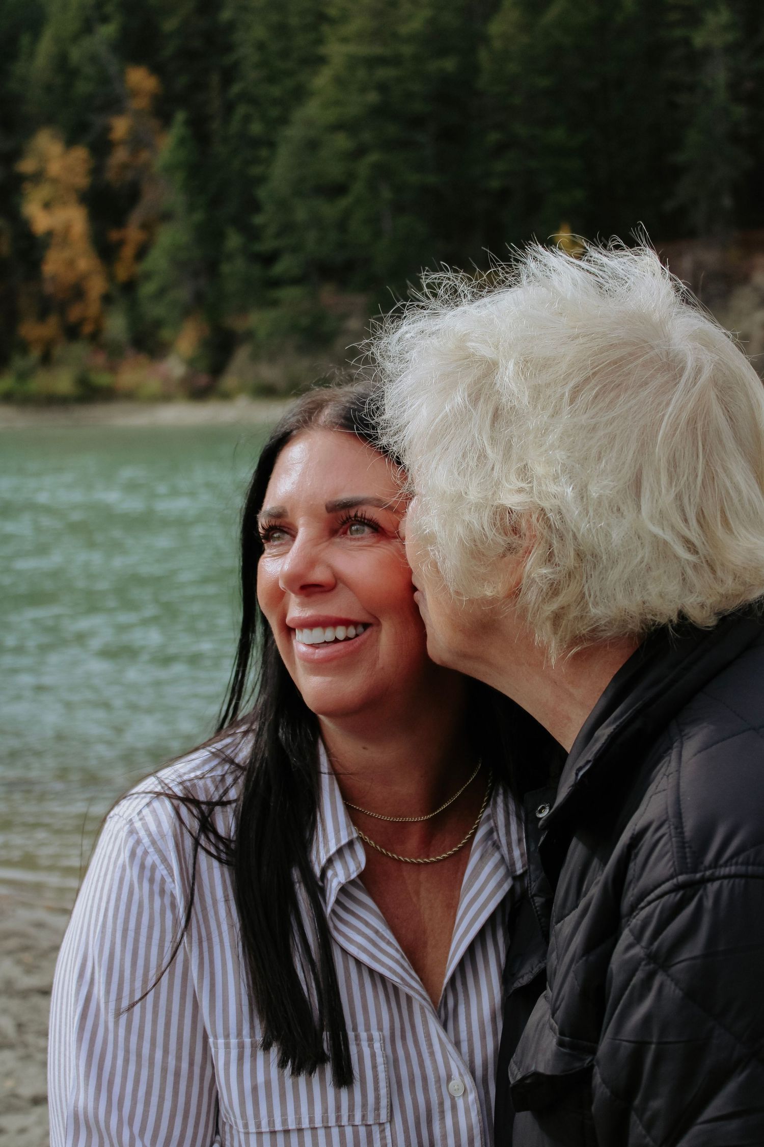 Candid expressions captured against mountain and lake backdrop.