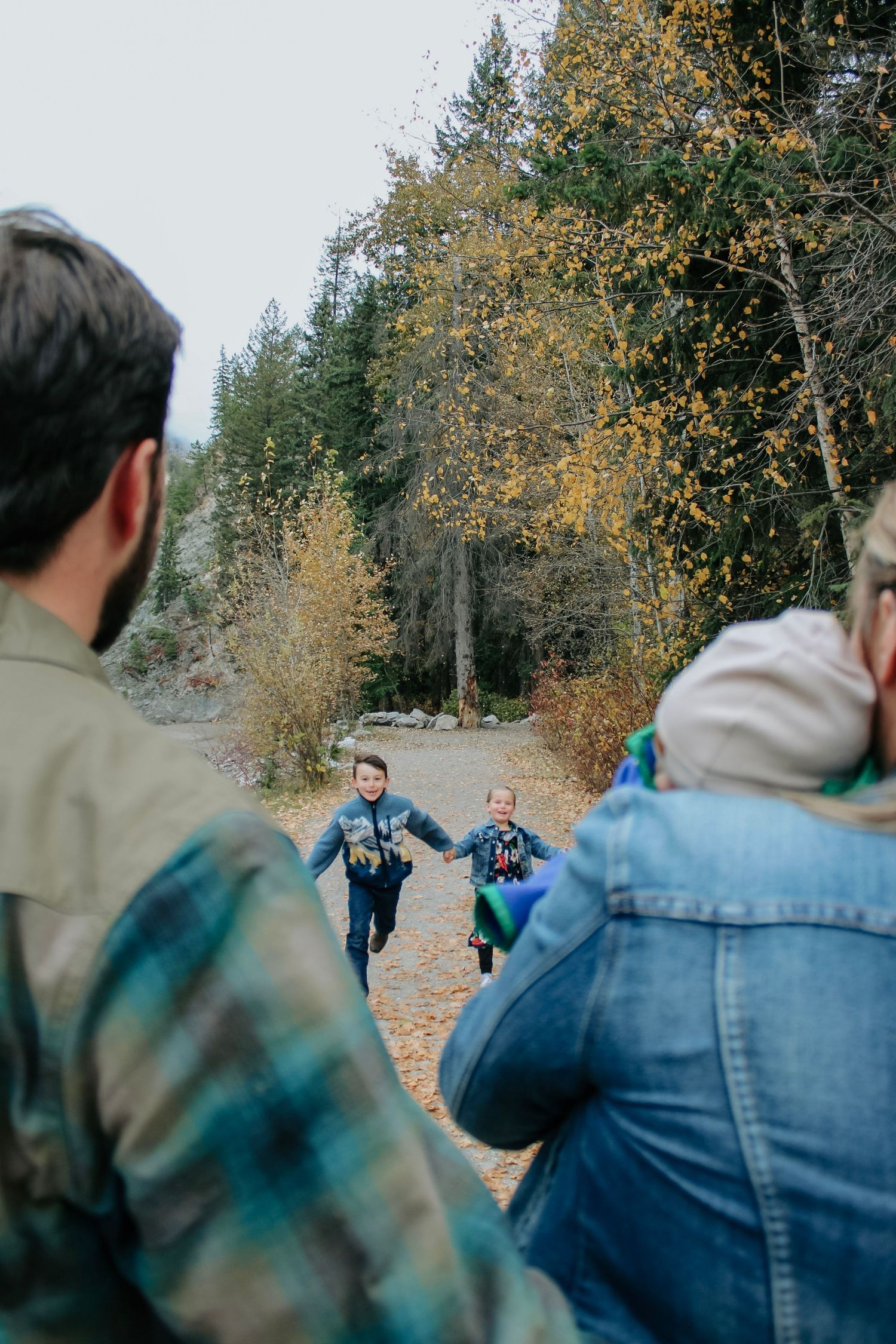 Group walking along a wooded path during fall with yellow leaves on trees.