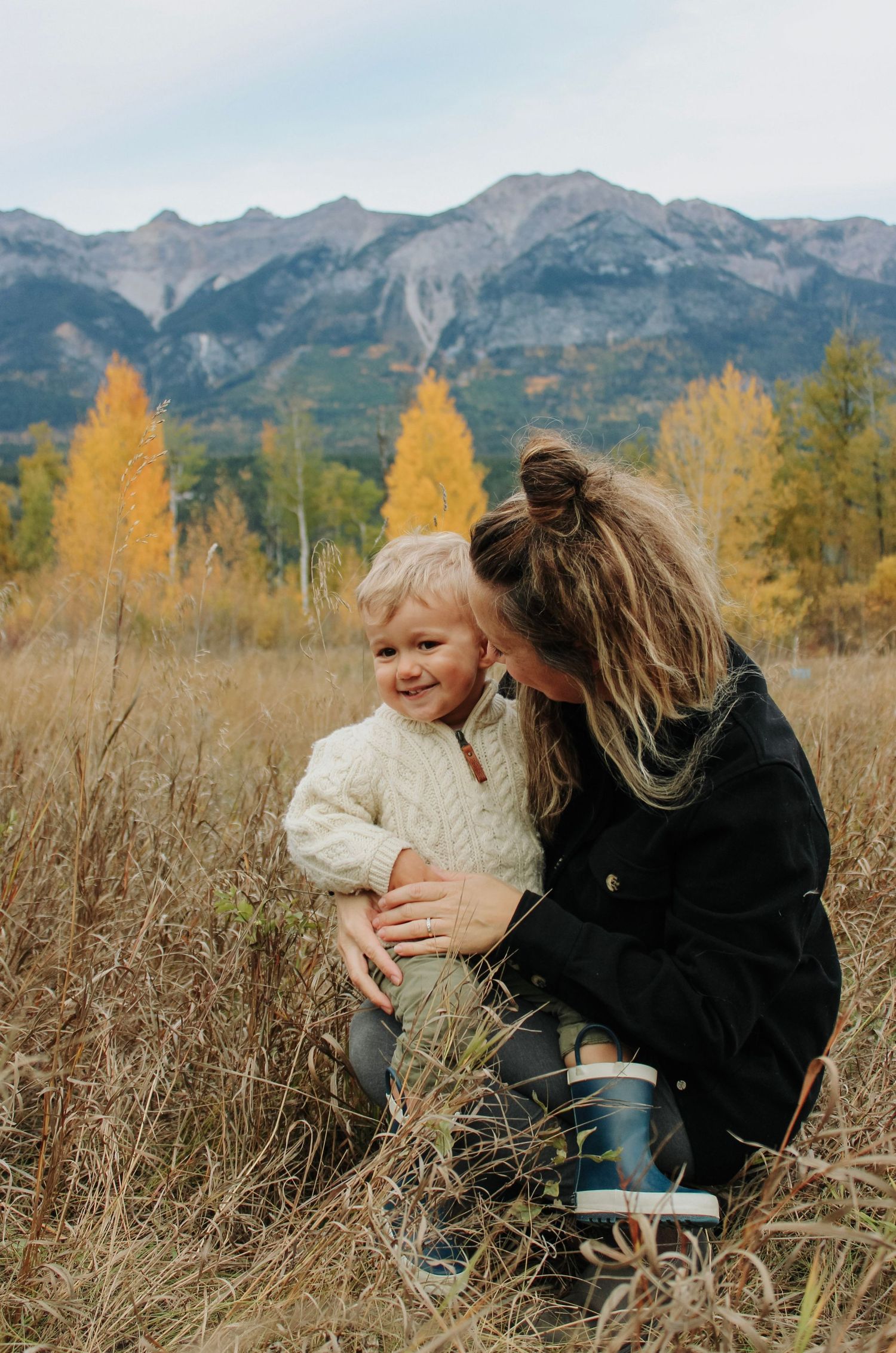 Joyful family interactions captured in mountain meadow during golden hour.