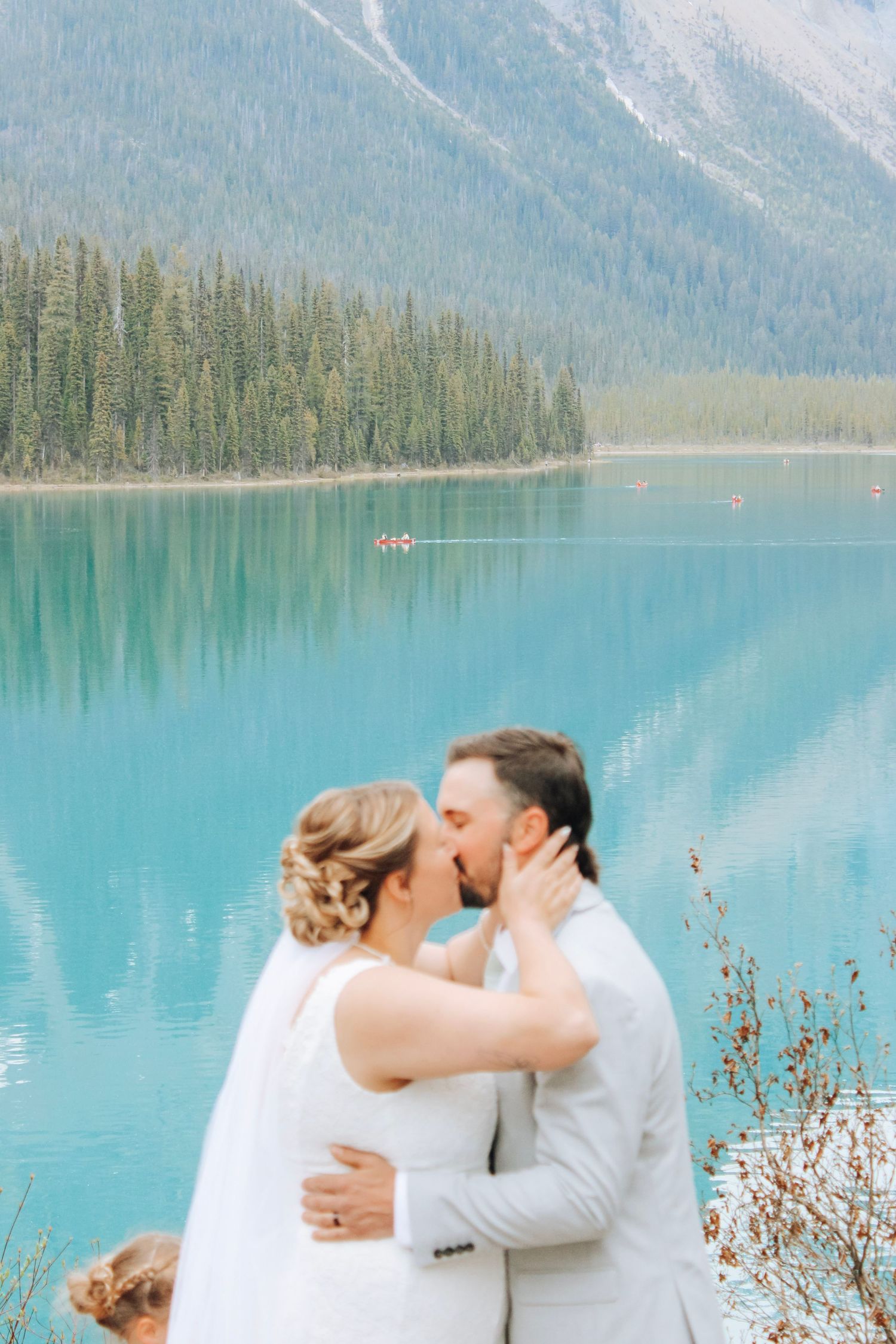 A romantic wedding moment captured against a stunning turquoise lake and mountain backdrop.