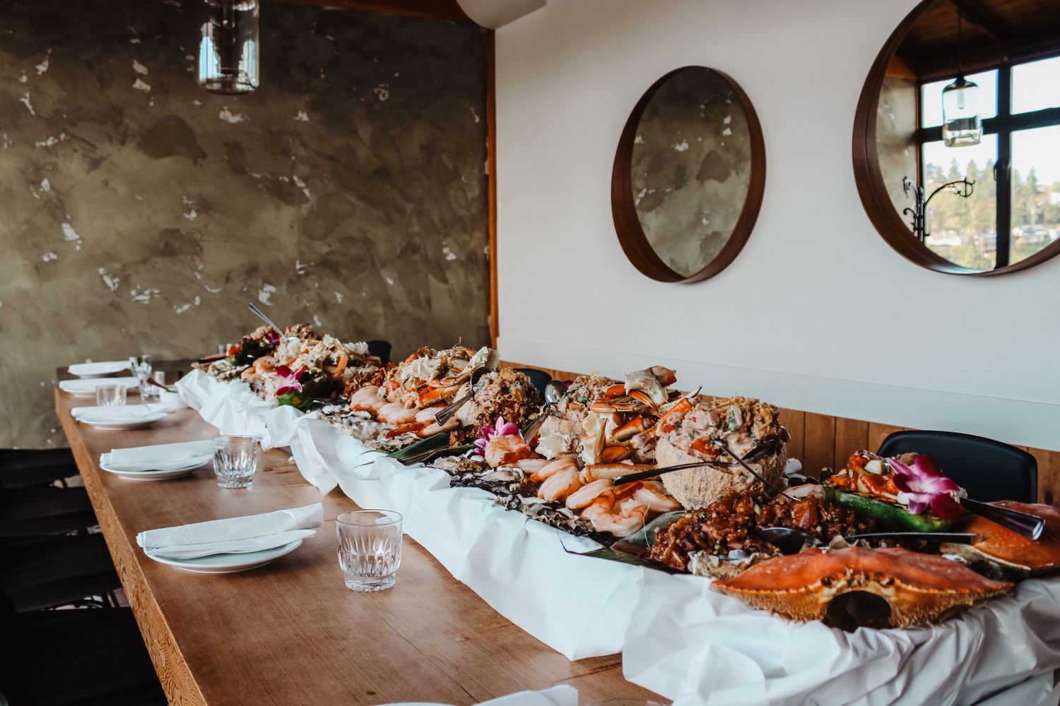 Long dining table with platters of food and place settings in a rustic venue.