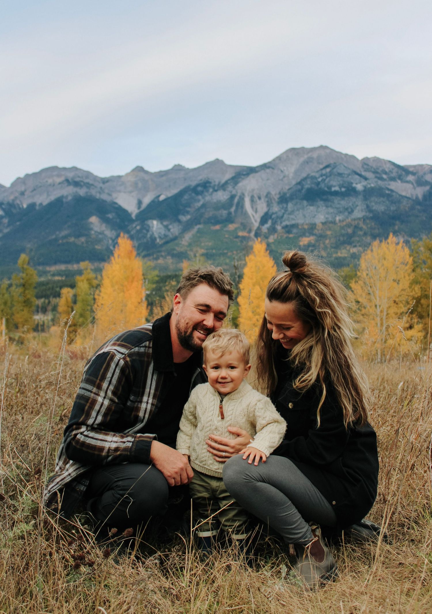 A family shares a happy moment together against a backdrop of autumn mountains.