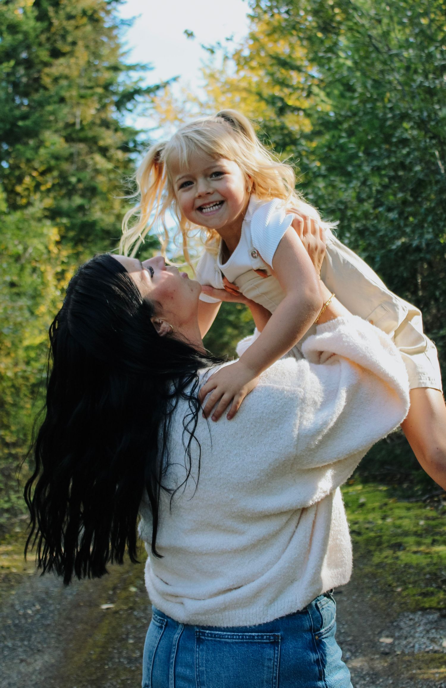 A joyful family moment captured outdoors with golden sunlight filtering through trees.