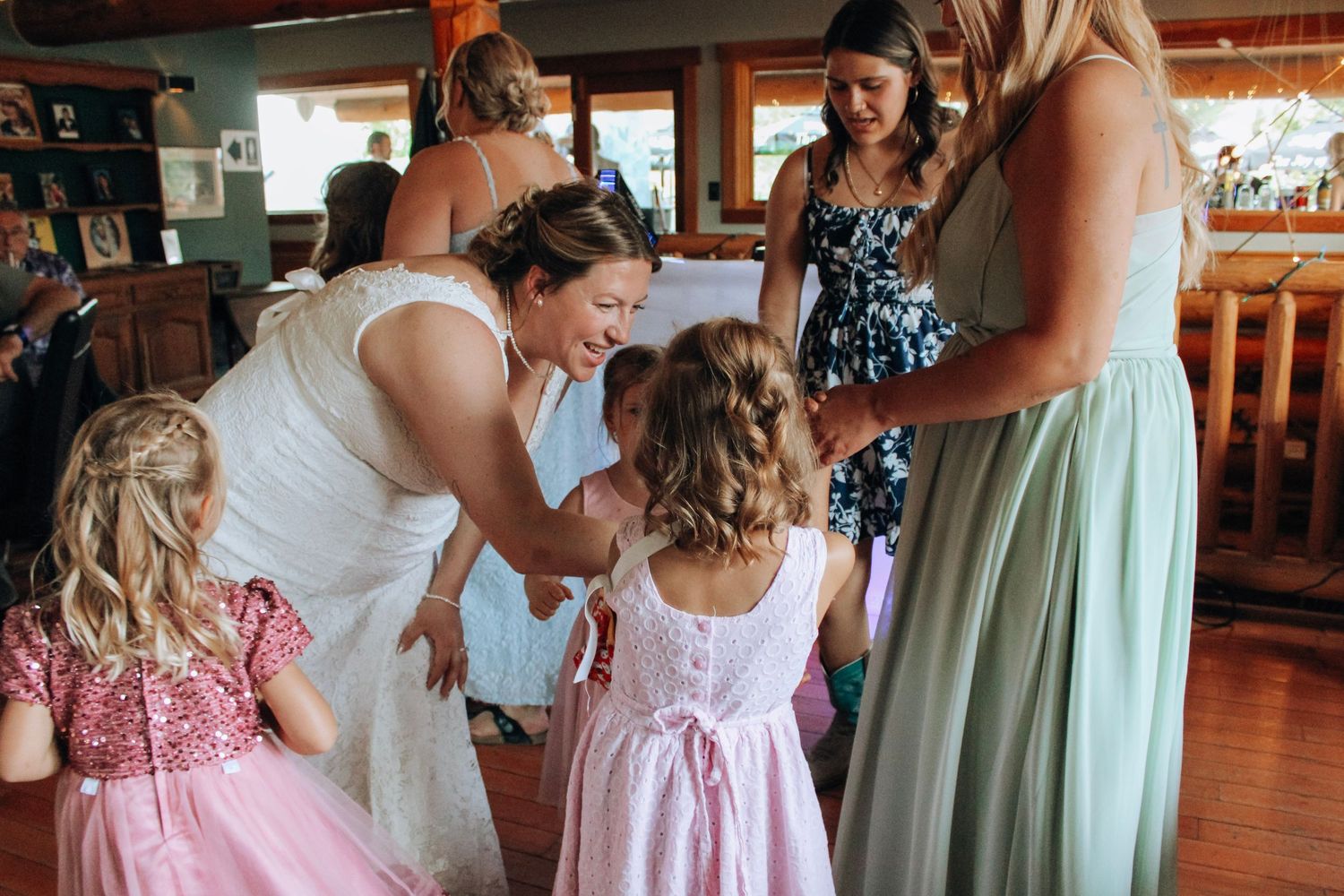 Bridesmaids in pastel dresses preparing for a wedding celebration in an indoor venue.