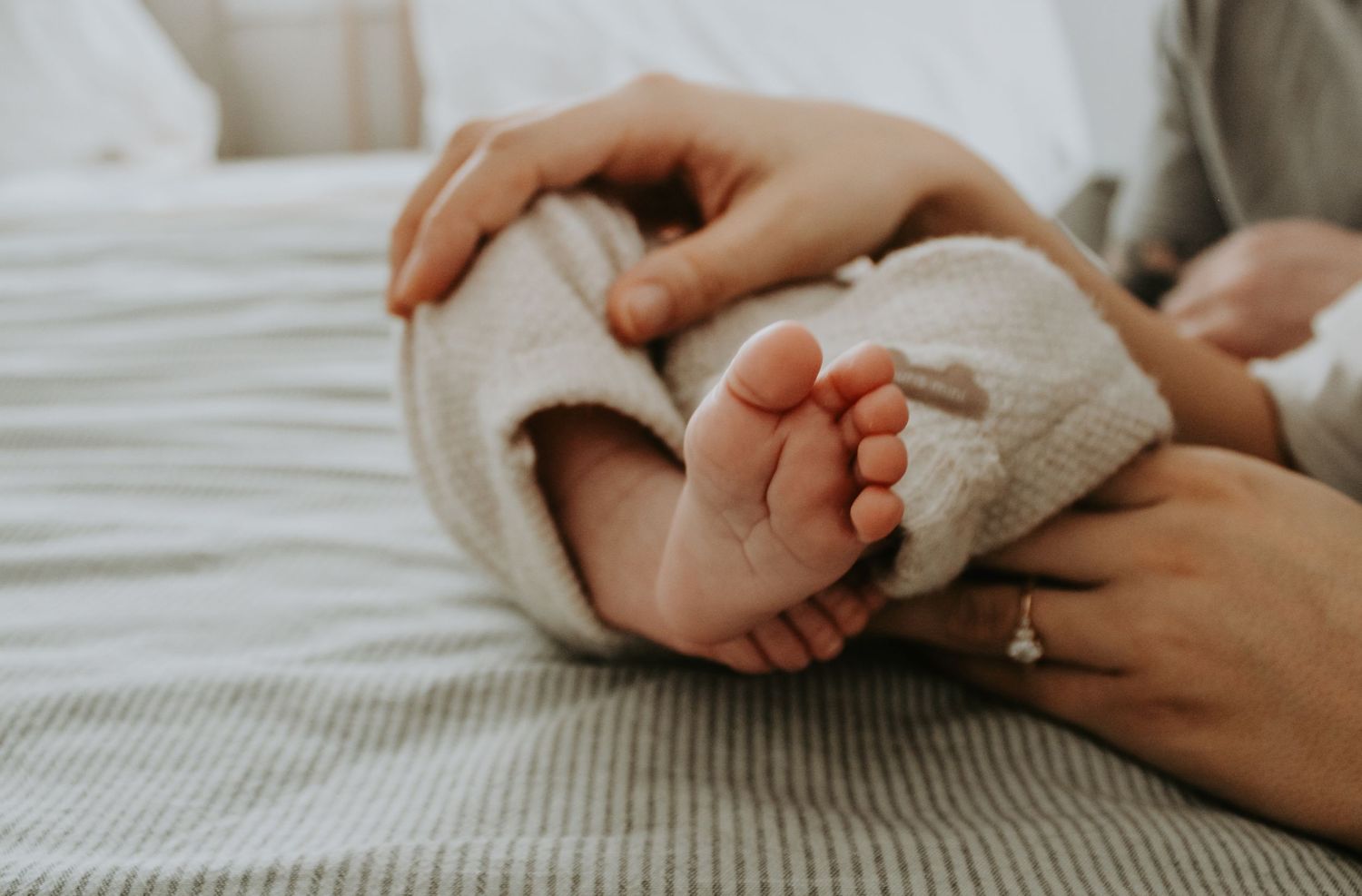 Close-up of hands gently touching on white bedding in natural light.