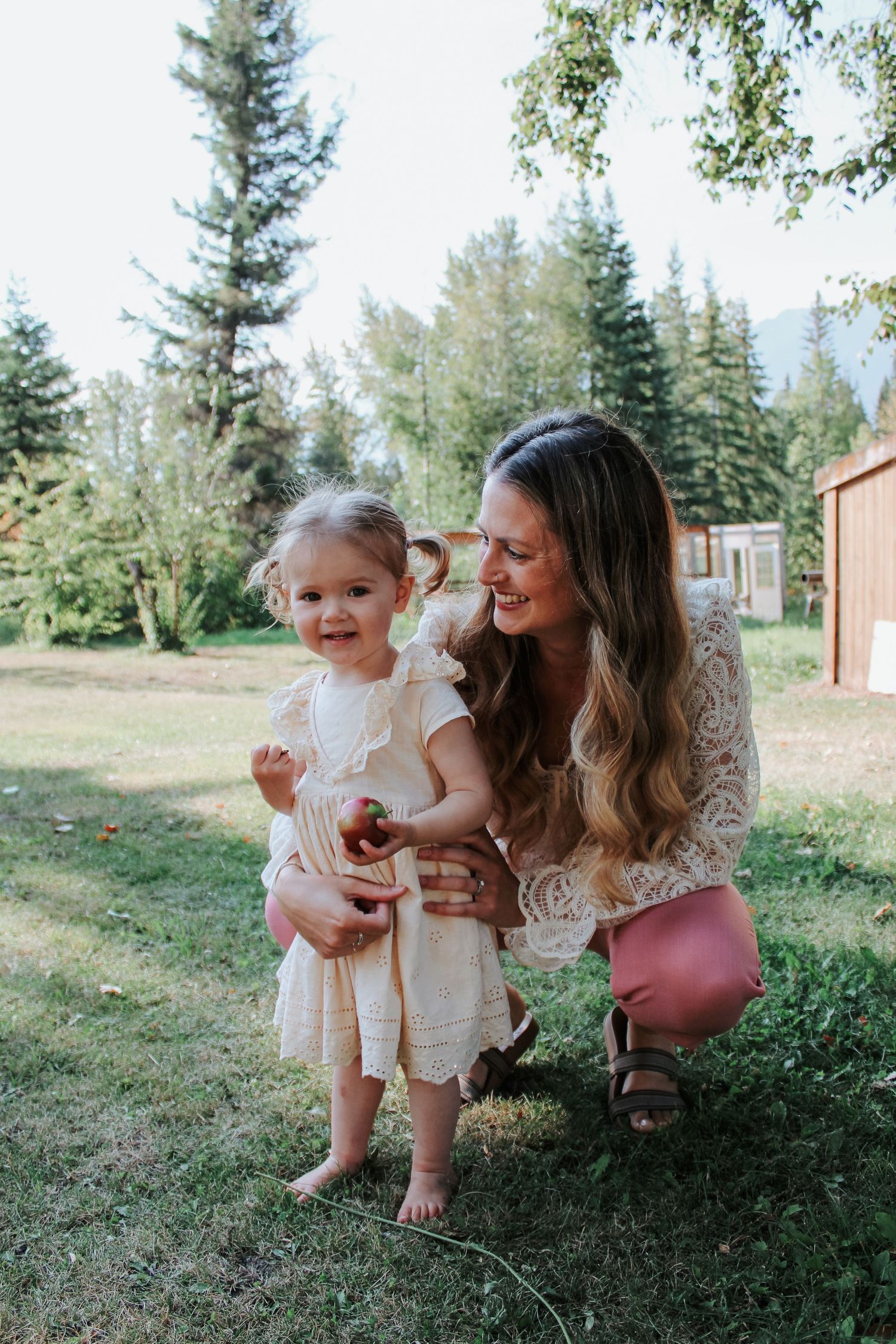 A joyful outdoor family photoshoot with greenery and pine trees in the background.