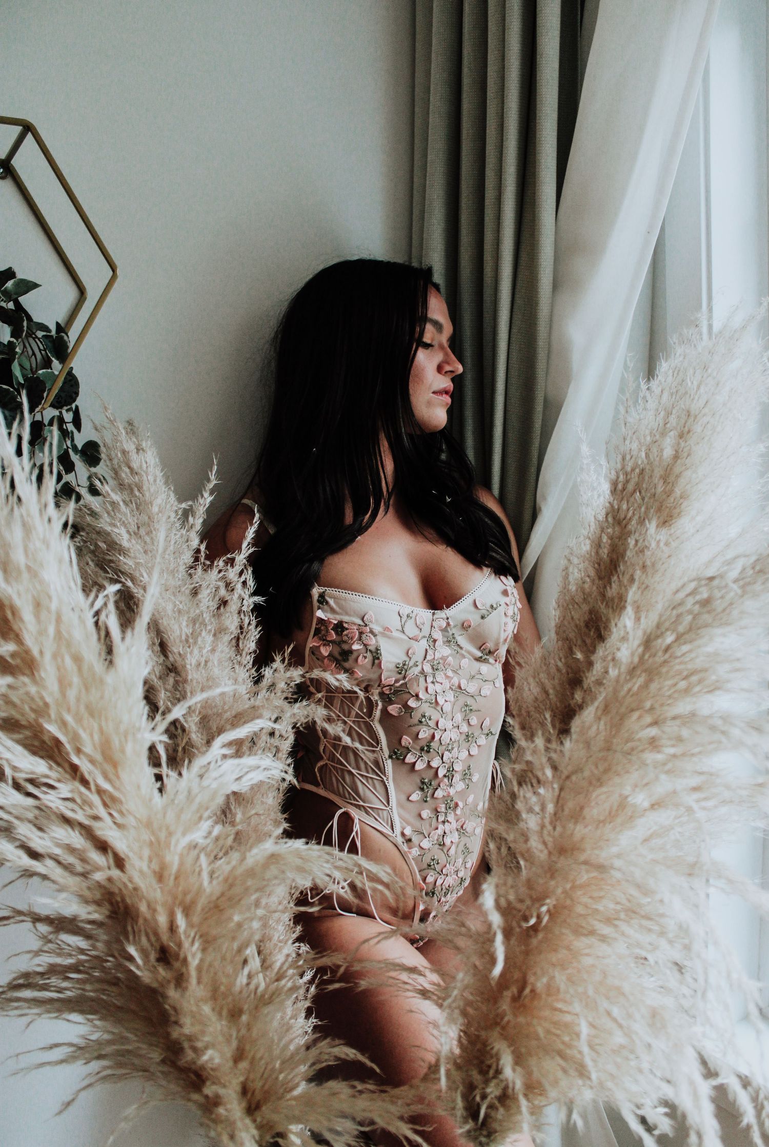 A boudoir photo with pampas grass and delicate lace details in soft lighting.