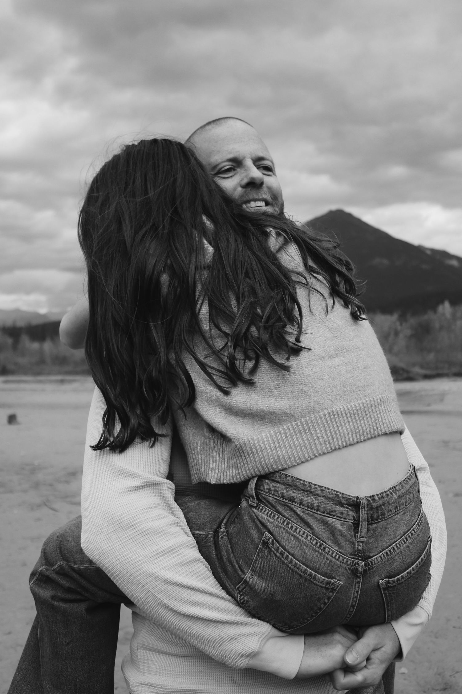 Black and white sequence of playful moments by the water with mountains in background.