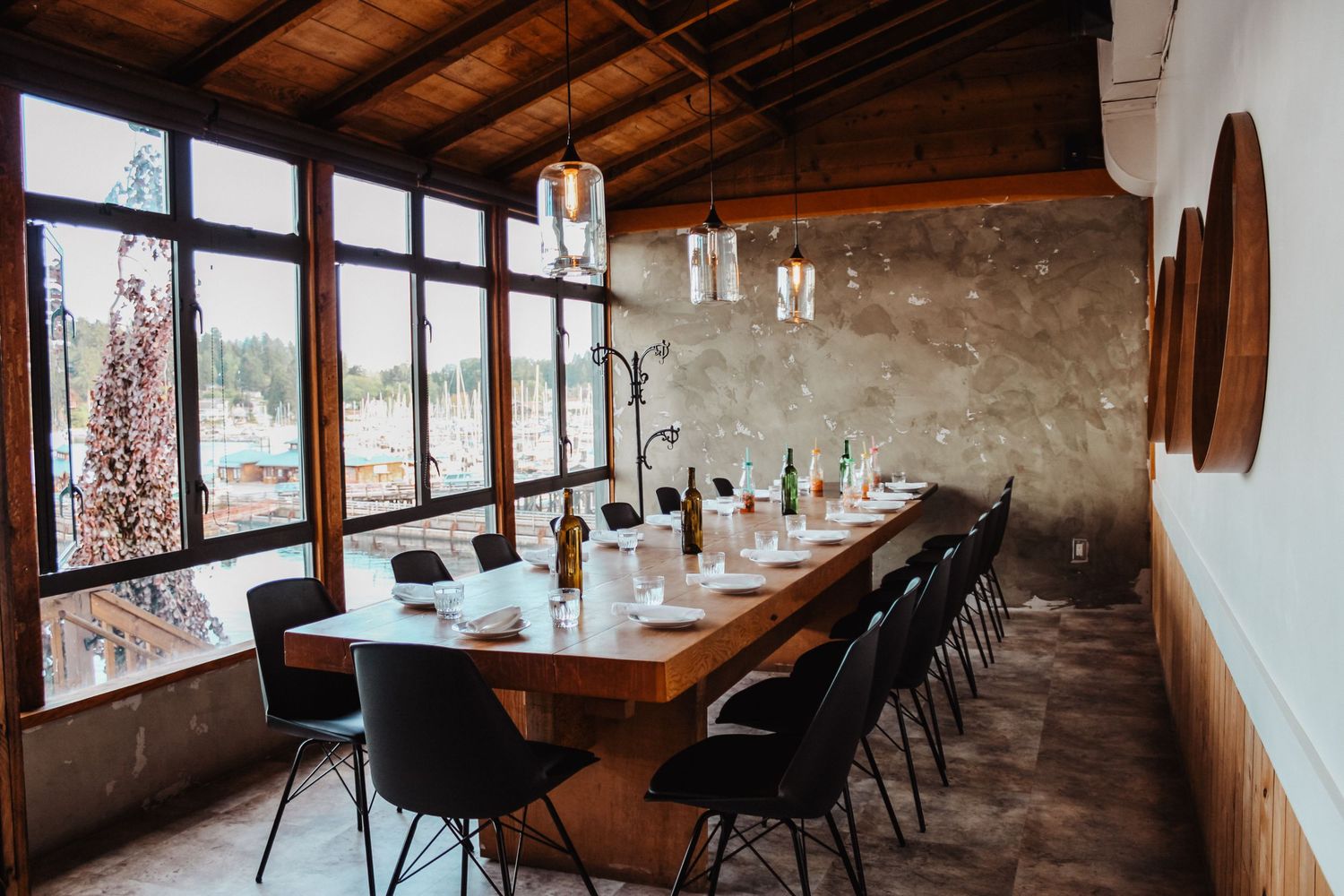 Panoramic view of a rustic dining room with wooden tables and modern black chairs.