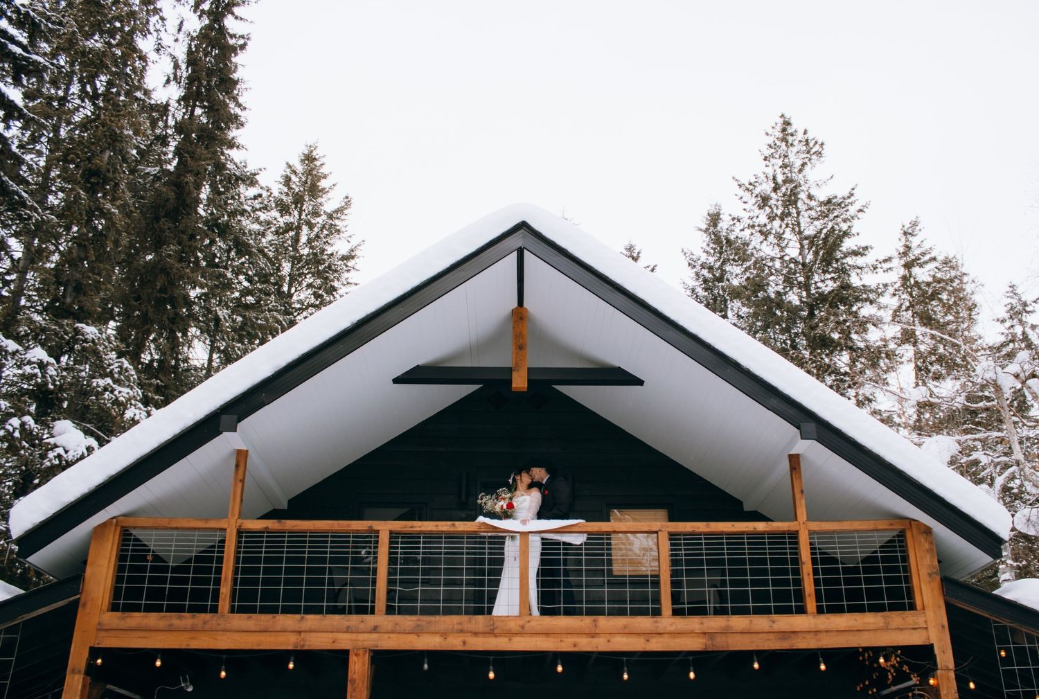 A panoramic sequence of a couple celebrating on a rustic cabin balcony surrounded by tall evergreen trees.