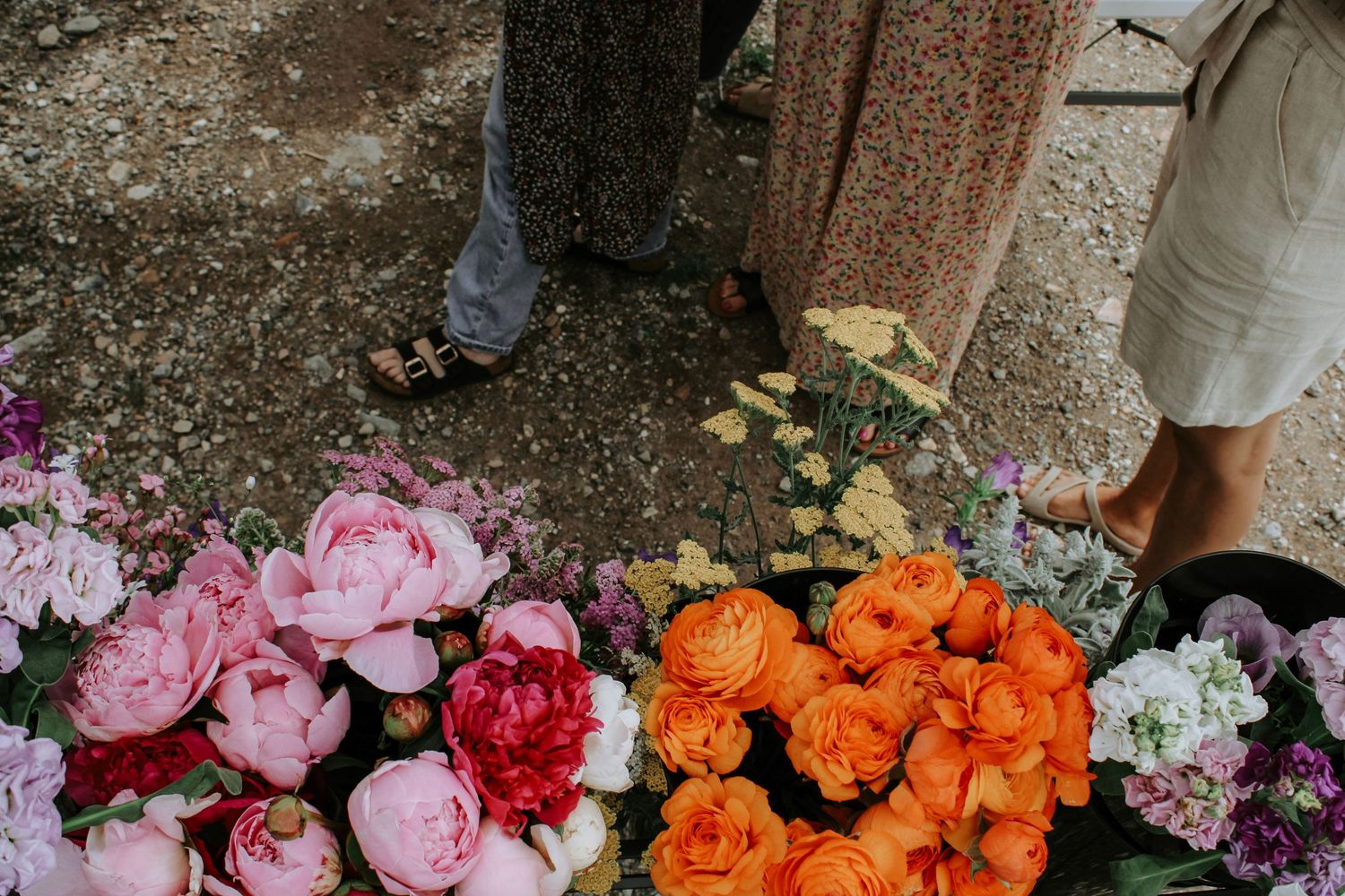 Colorful floral arrangements featuring pink, orange, and purple flowers displayed at an outdoor market.