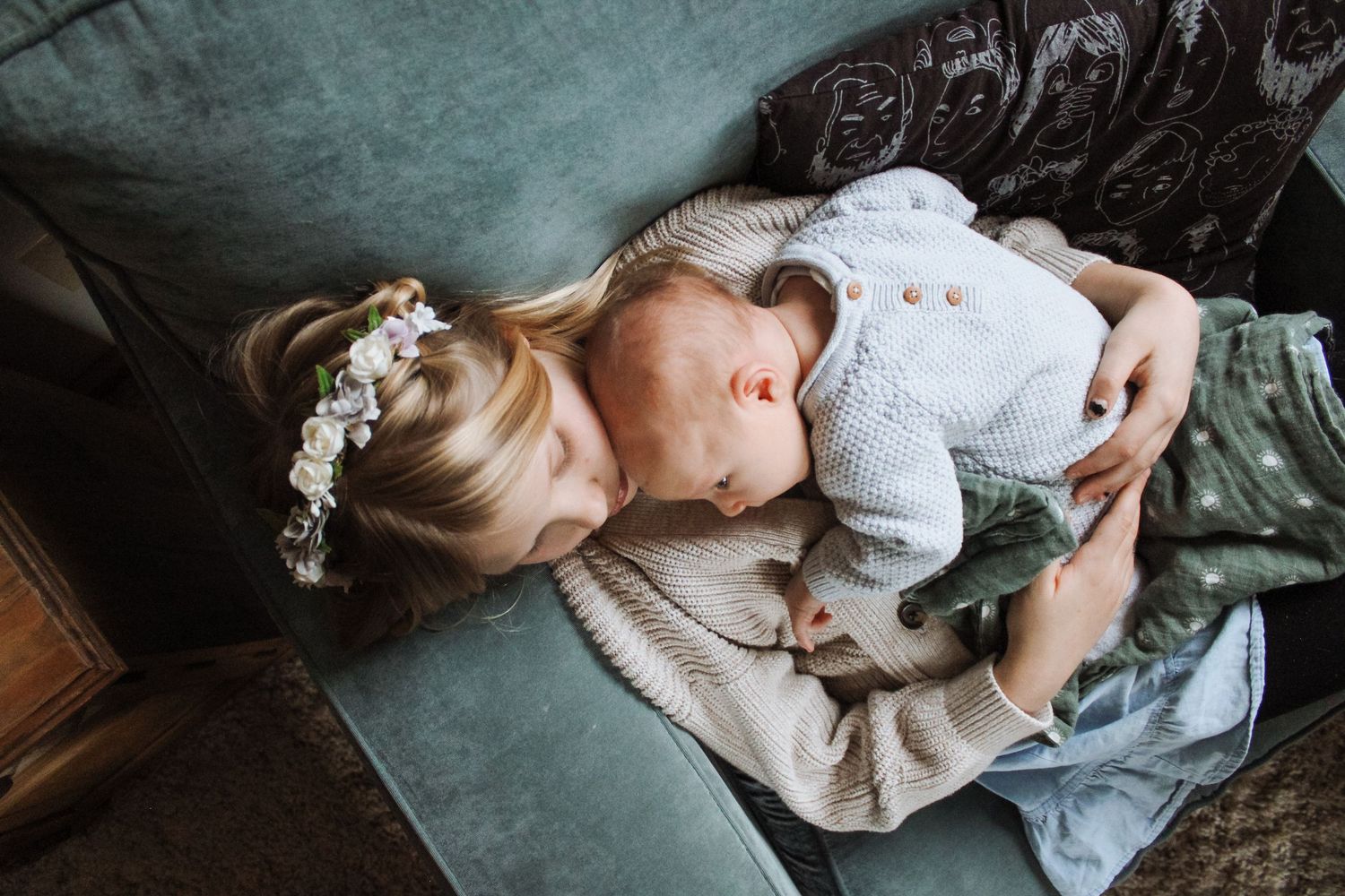 Intimate indoor portrait session showing tender moments on a couch in muted lighting.