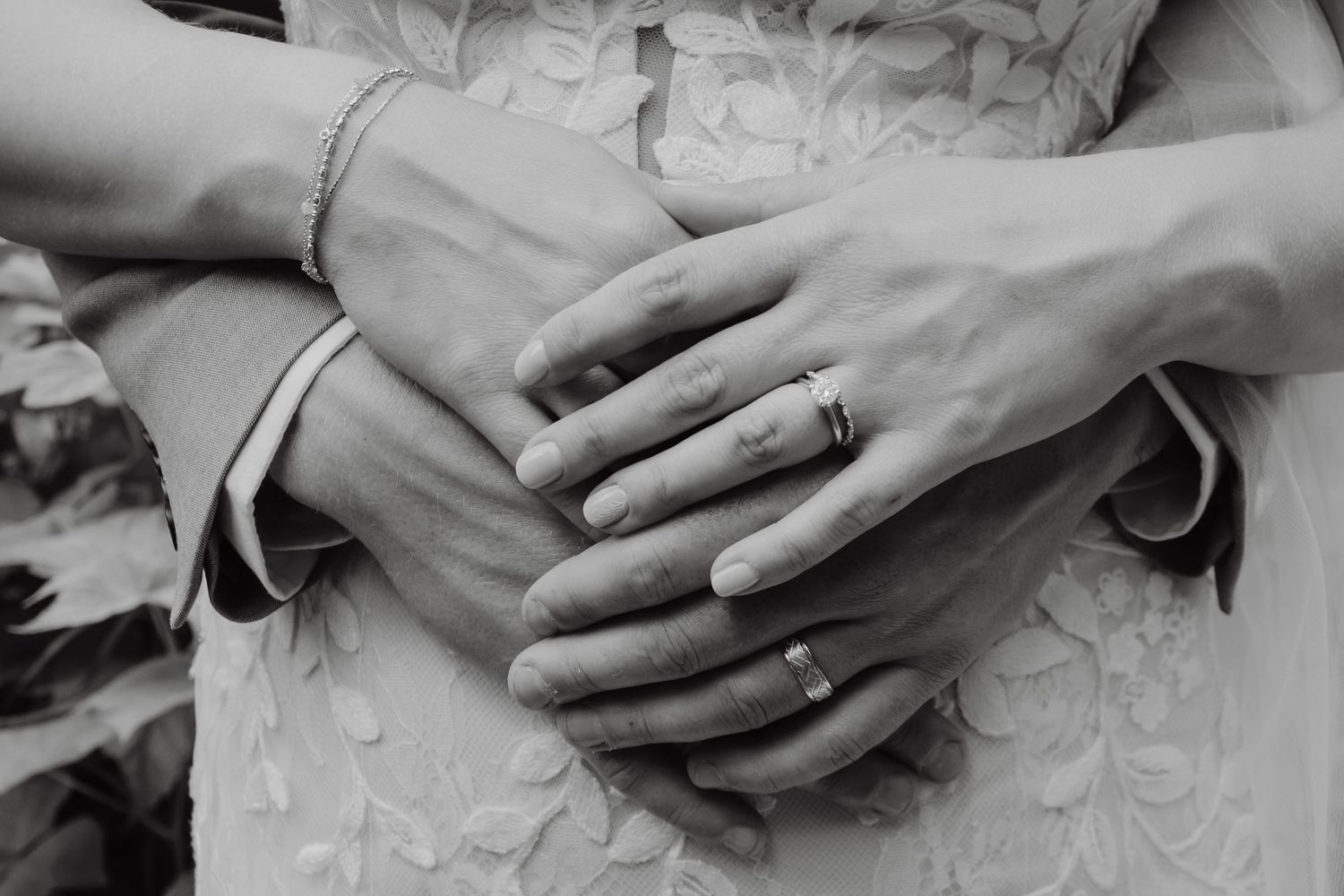 Close-up black and white photo of newlyweds hands showing wedding rings.