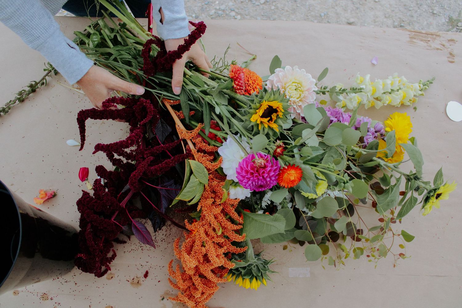 Fresh cut flowers laid out on a wooden surface with vibrant orange, pink and yellow blooms.