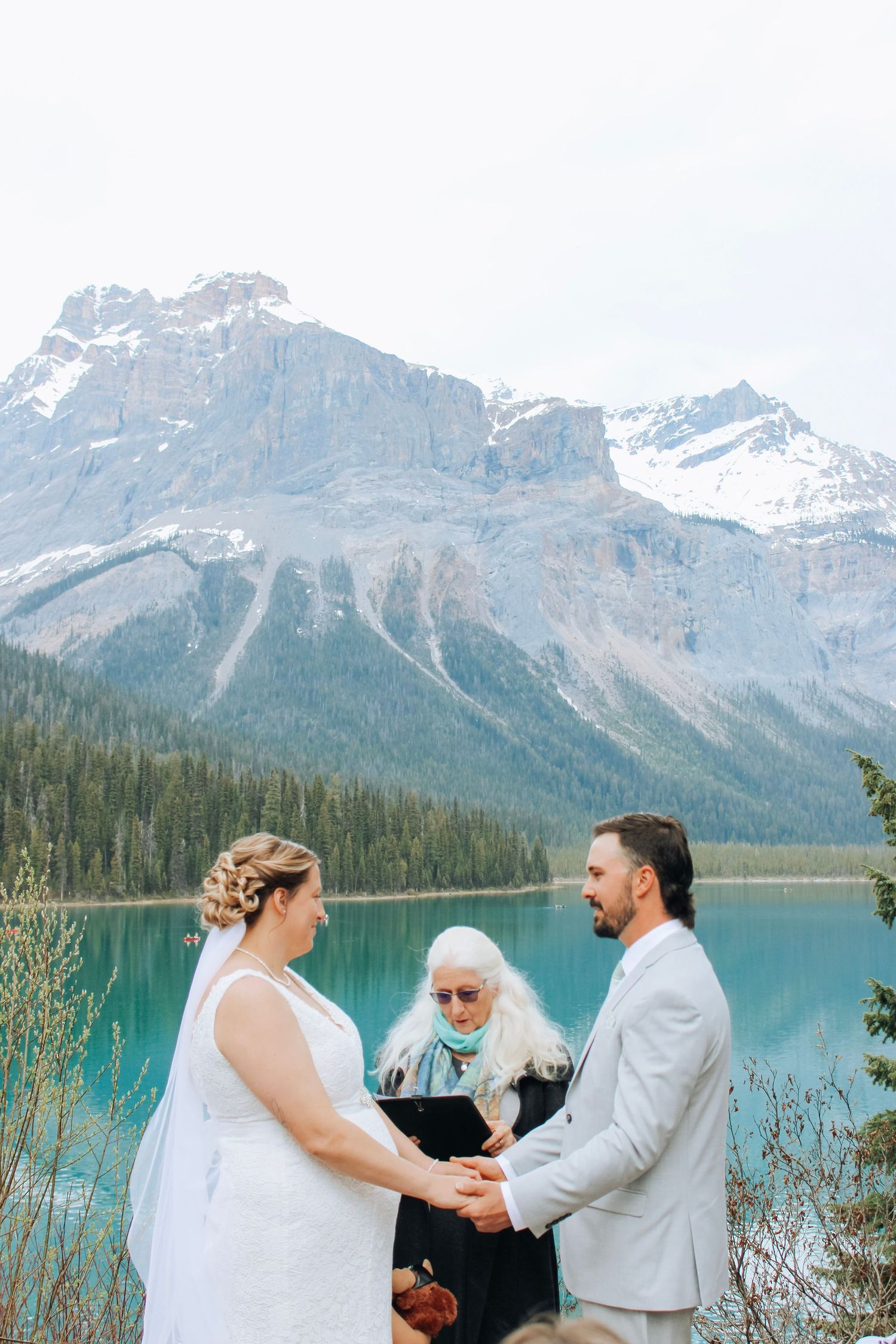 Mountain lake wedding ceremony with dramatic peaks and turquoise waters in background.