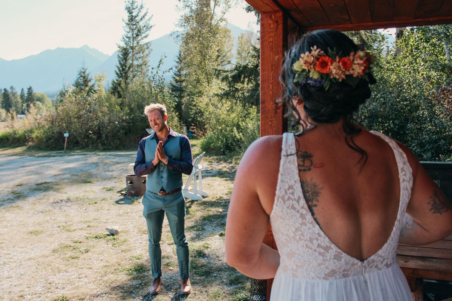 Romantic outdoor wedding moment captured under a rustic wooden structure with mountain views.