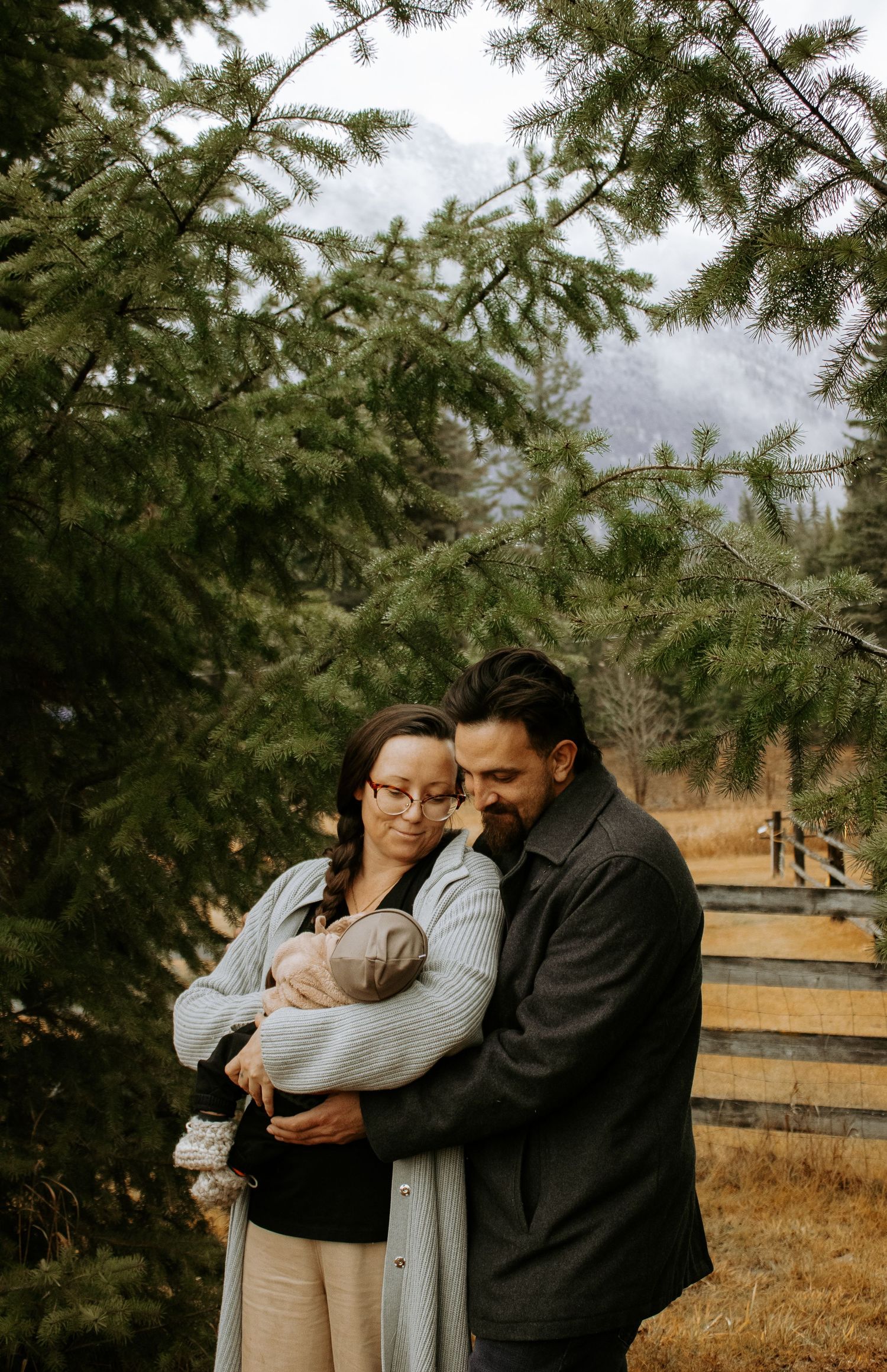A tender family moment captured against an evergreen forest backdrop.