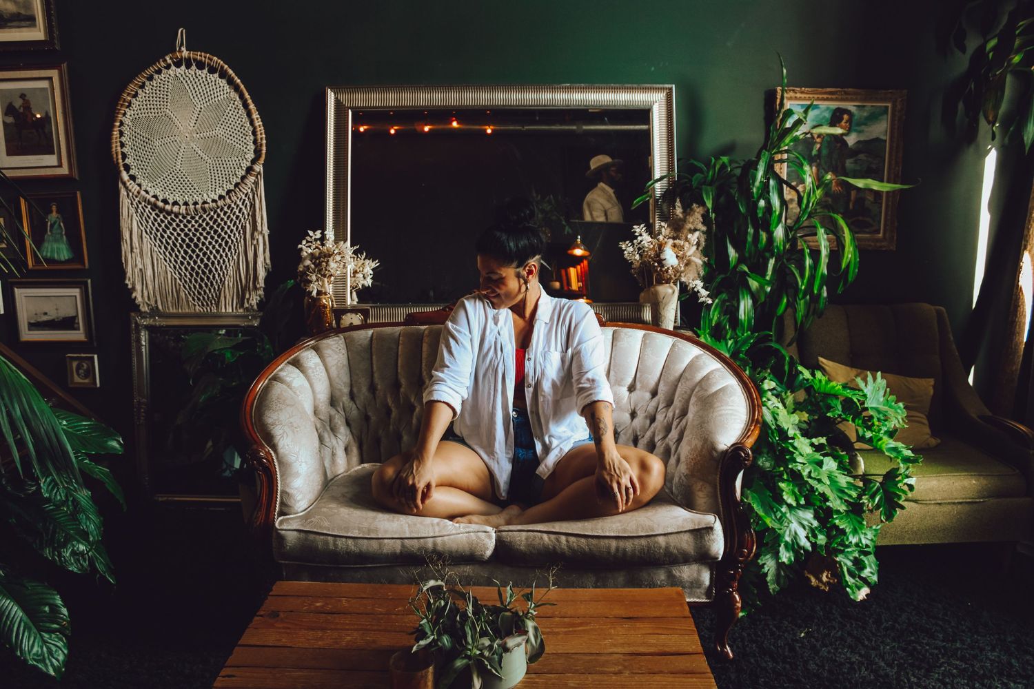 A cozy dimly lit bar interior with vintage decor, wooden furniture, and hanging plants creates an intimate atmosphere.