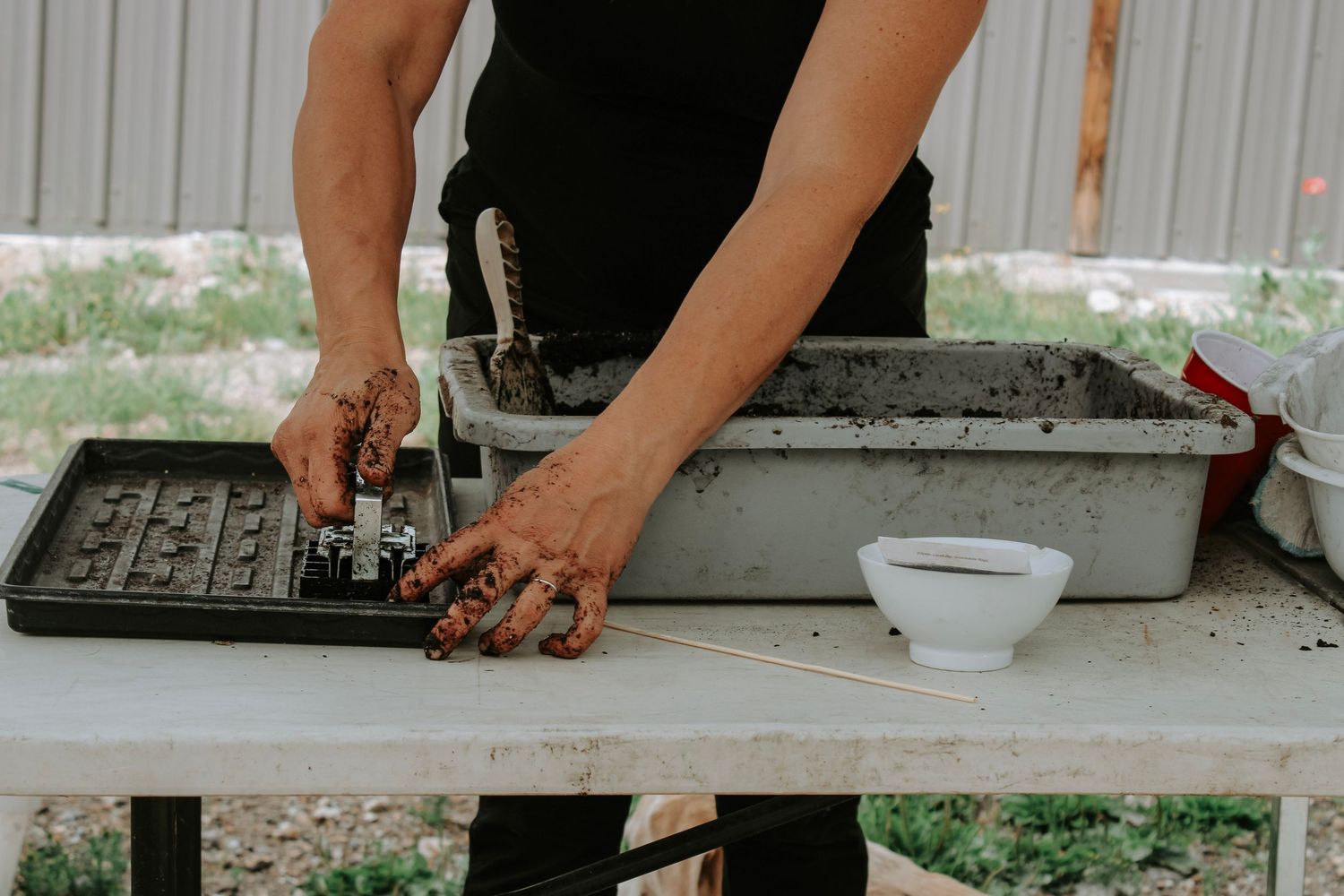 Hands arranging and preparing fresh cut flowers on a work surface.