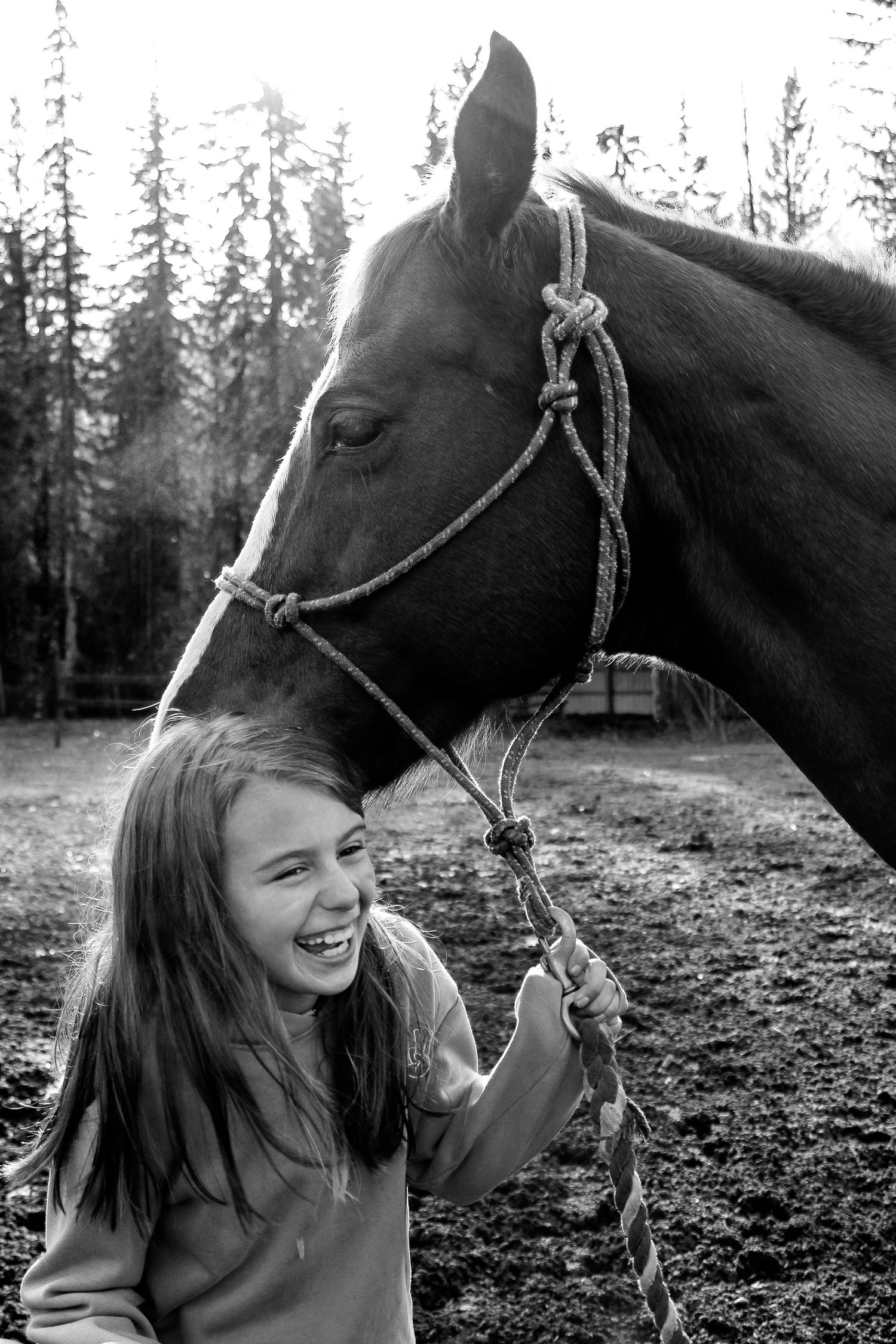 Candid black and white moments captured with a horse in a forest clearing.