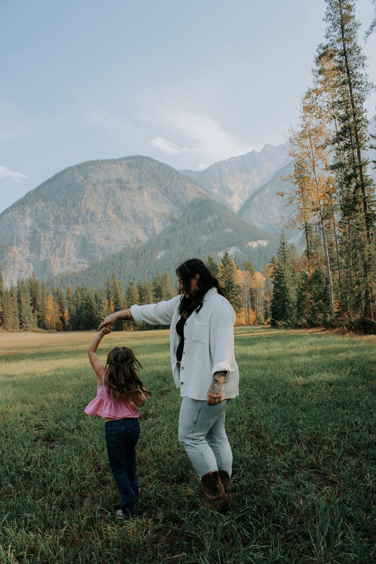Dynamic family photoshoot with mountain peaks and forest backdrop.