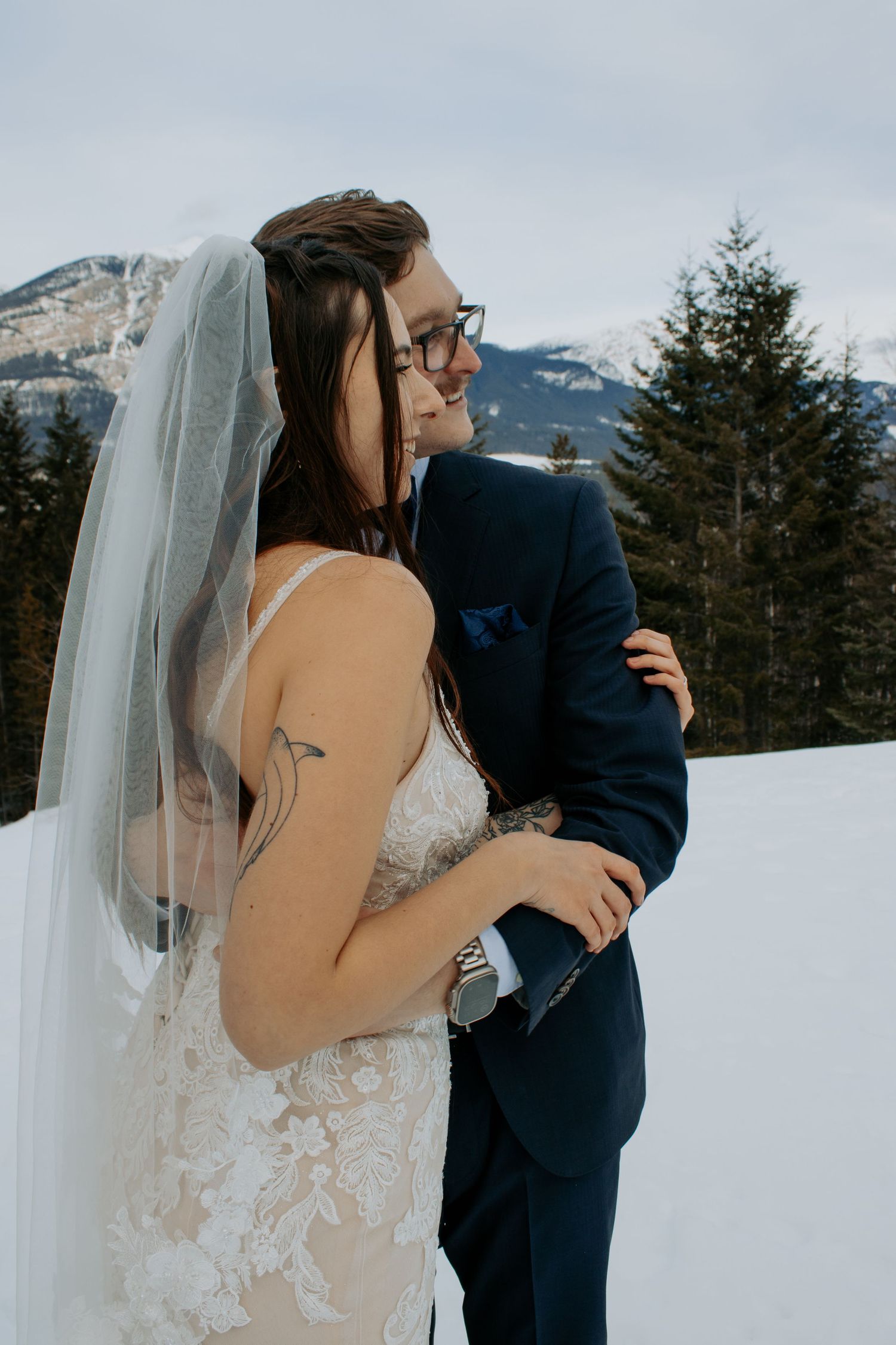 A couple shares an intimate first look moment against a snowy mountain backdrop during their winter wedding celebration.