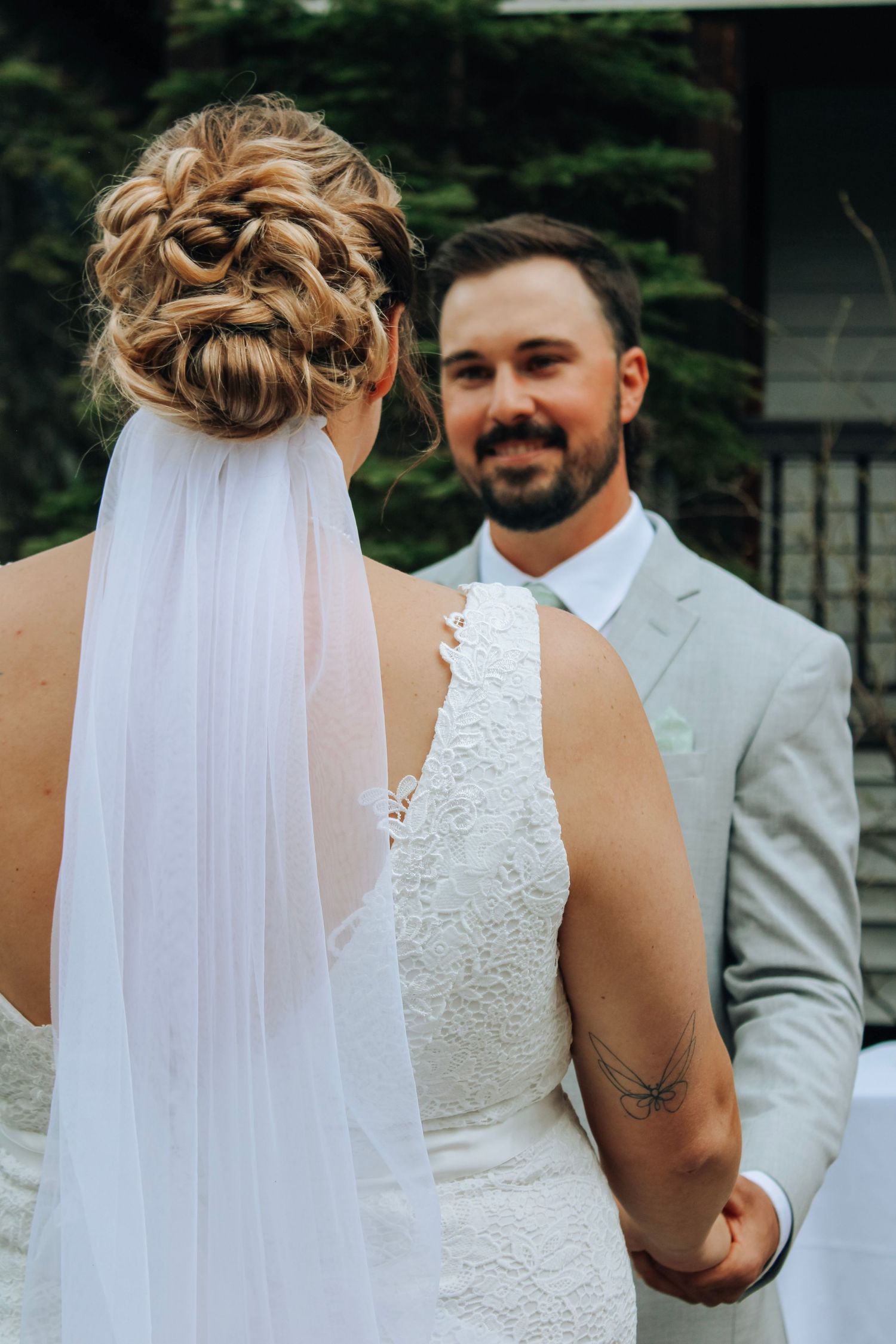 Intimate wedding ceremony details with bride in lace dress and groom in light suit.