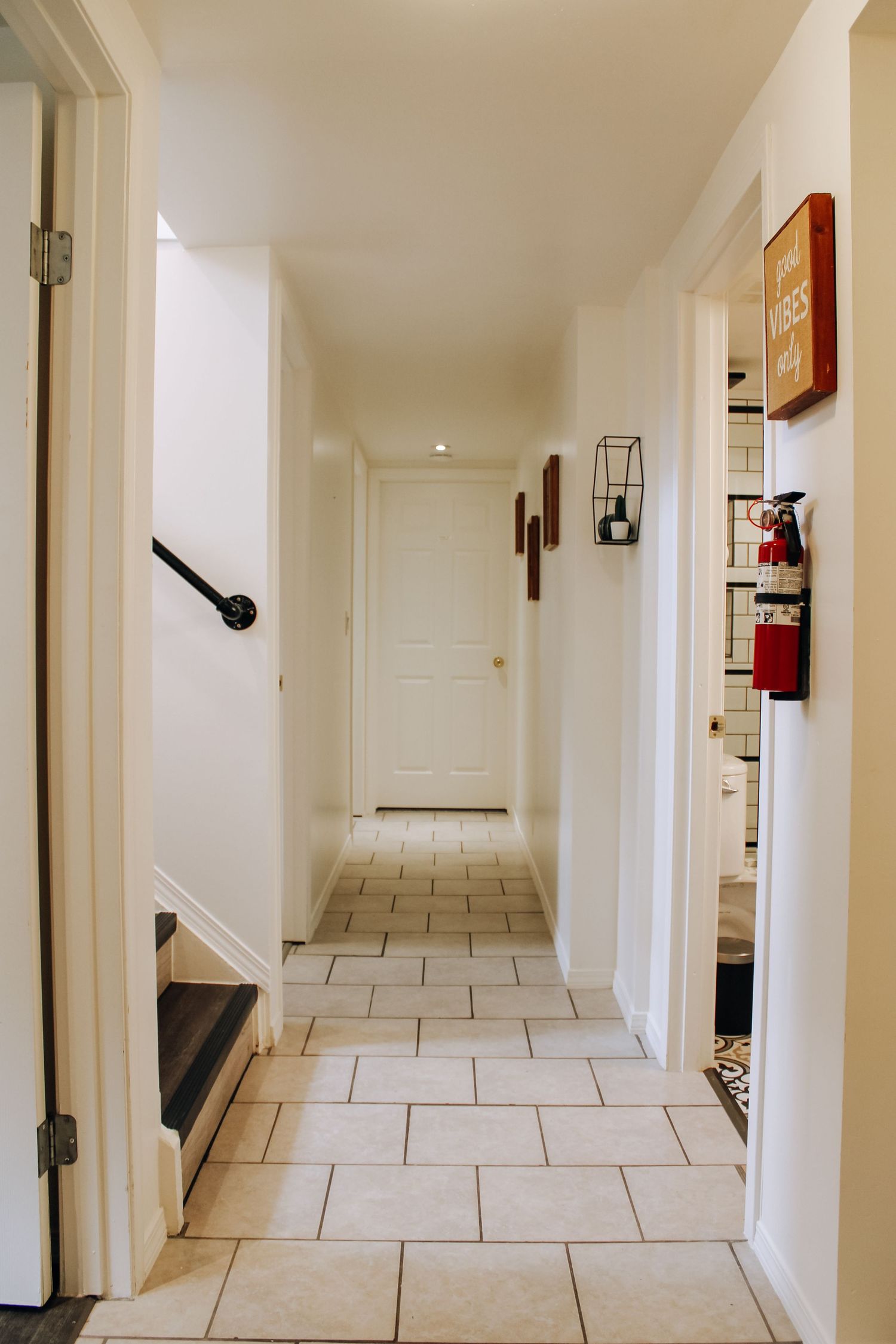 Long white tiled corridor with multiple doorways and minimal wall decorations.