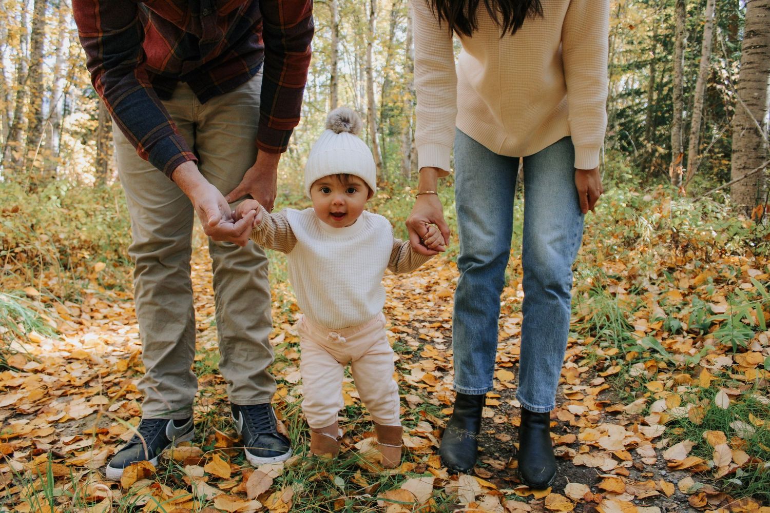 Feet and legs of people standing together on fallen autumn leaves in a forest setting.