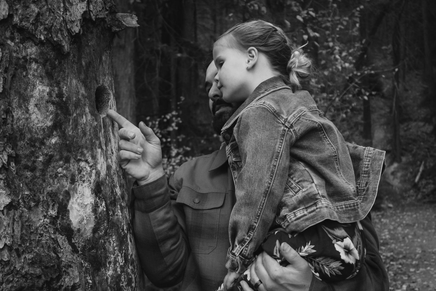 Intimate black and white portrait against a dark forest backdrop.