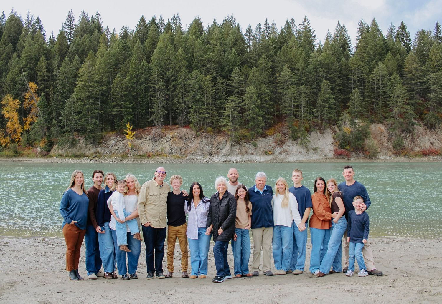 Group photo in front of evergreen forest and mountains with turquoise water.