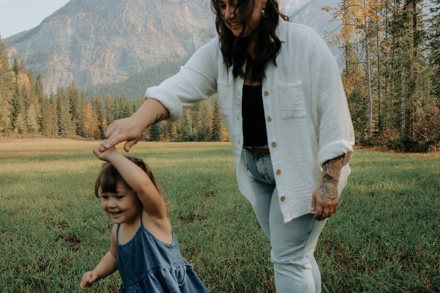 Playful movement sequence captured in mountain meadow with dramatic landscape.