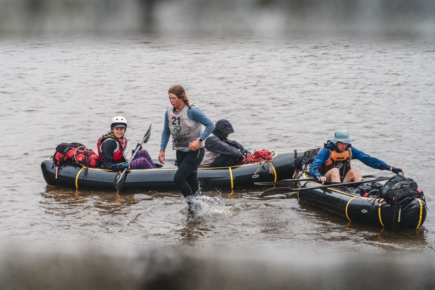 a group of athletes, stopping their packrafts to get to a check point on an adventure race.