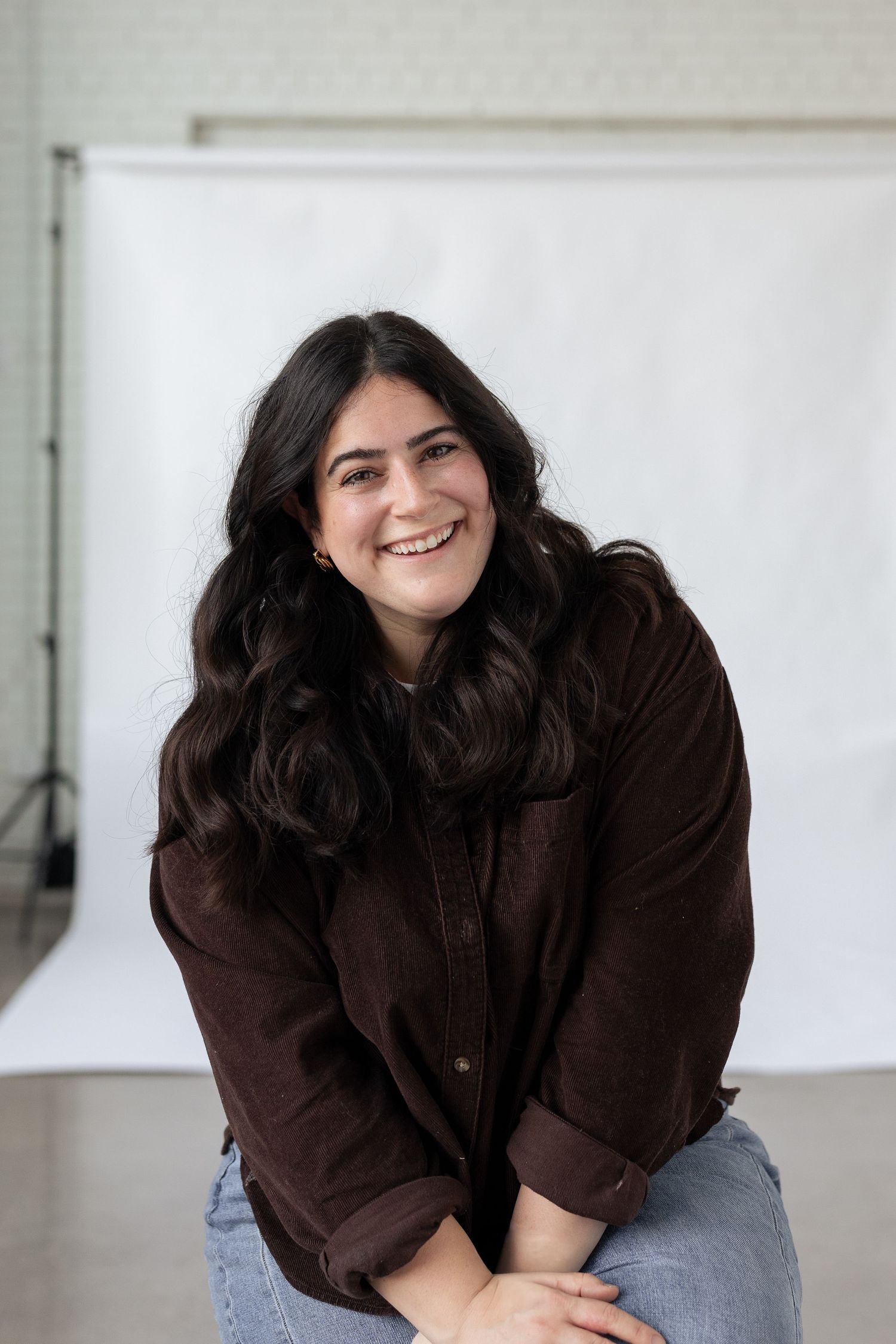A casual portrait featuring a brown corduroy jacket and denim in a bright studio setting.