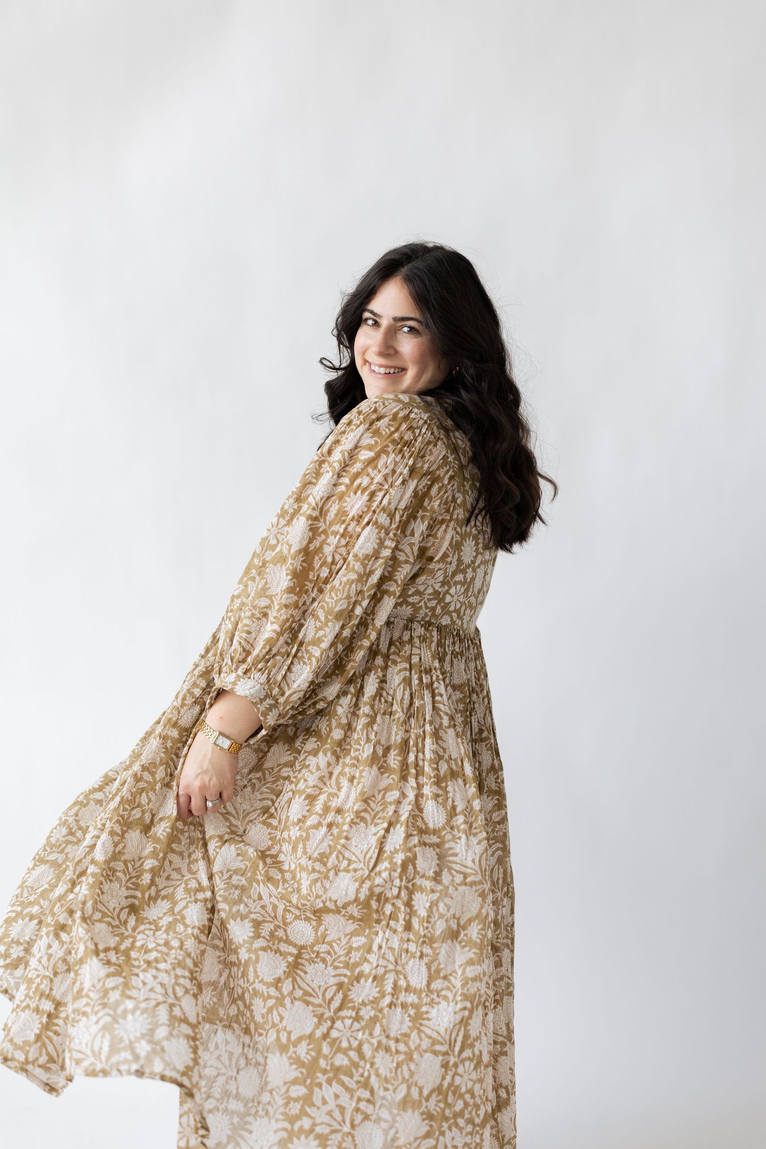 A flowing beige patterned dress moves gracefully in a studio setting.