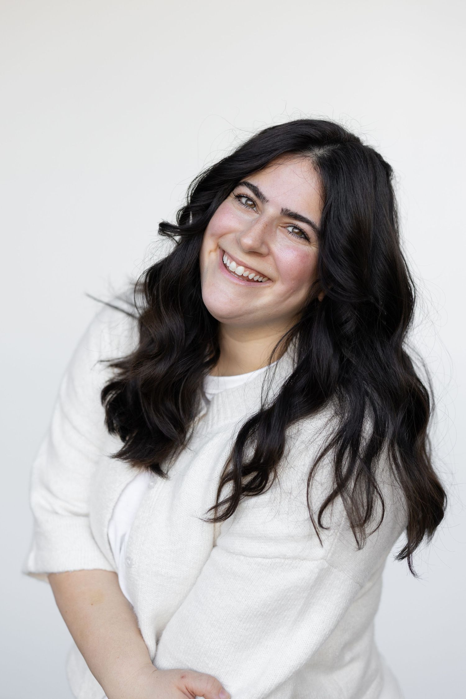 A casual portrait in a white sweater against a minimalist background.