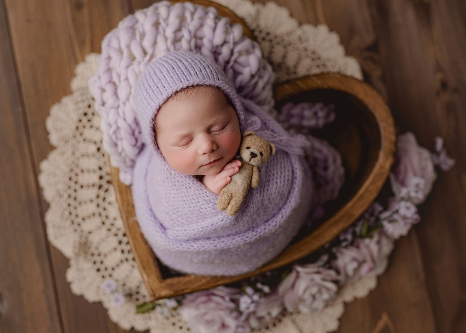 A collage of newborn photography showing a baby wrapped in purple swaddle on wooden backdrop with lace accents.