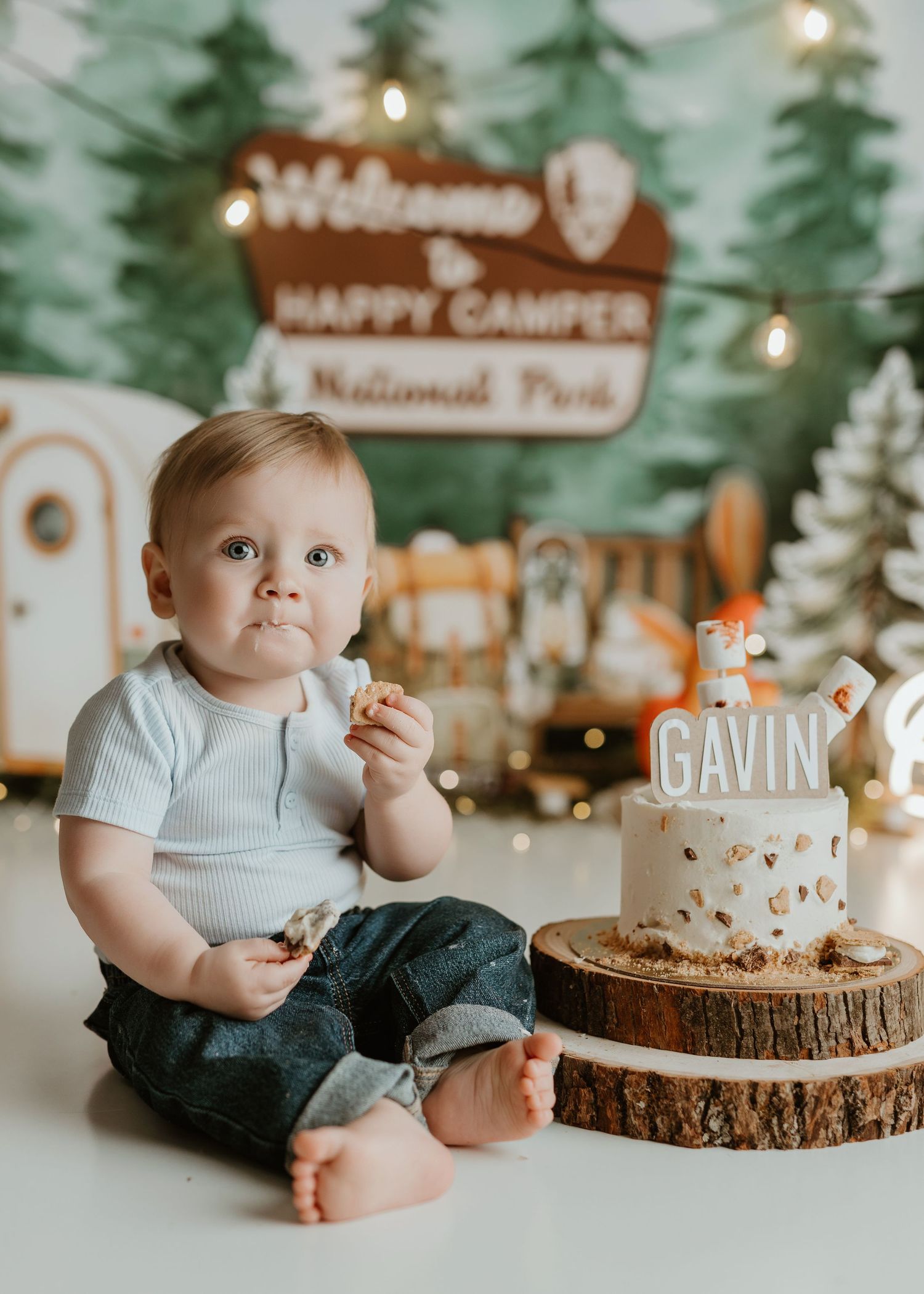 Baby boy Gavin sits beside his first birthday cake at a Happy Camper National Park themed cake smash photo session.