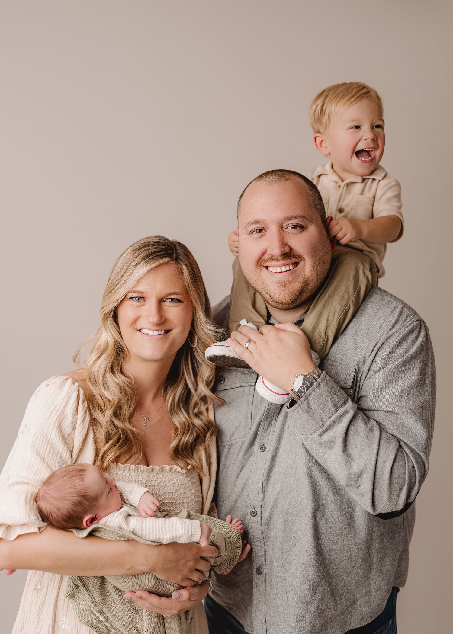 A family laughs together while posing for a series of candid photos in neutral tones.