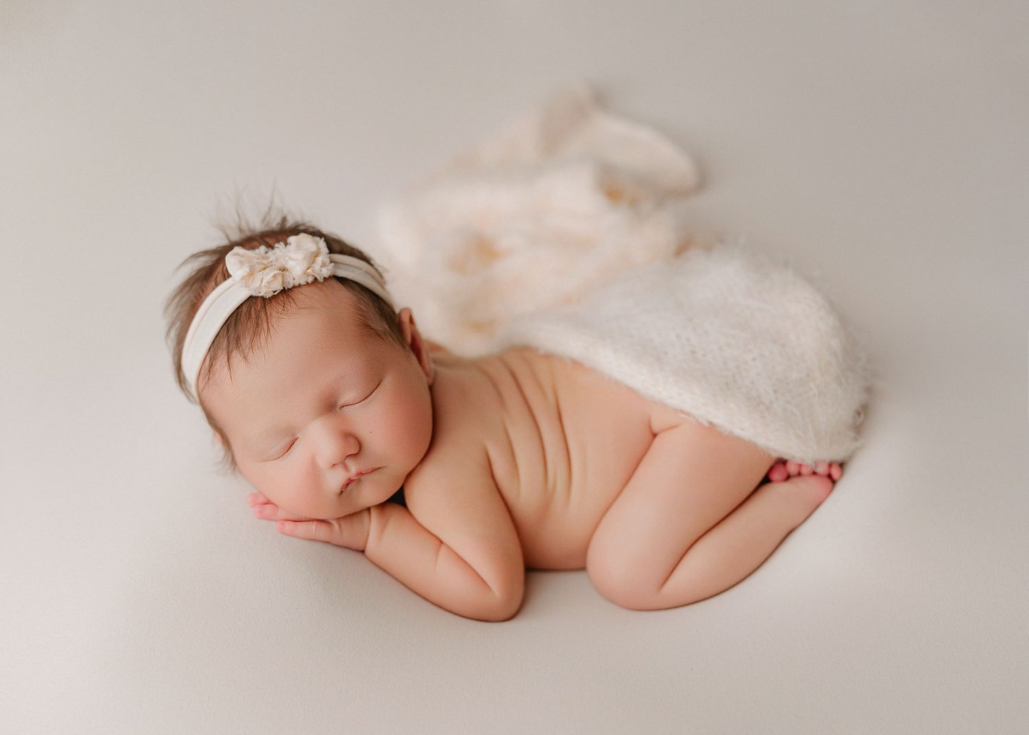 A series of soft, dreamy newborn photography portraits showing tiny feet and sleeping baby against cream backgrounds.