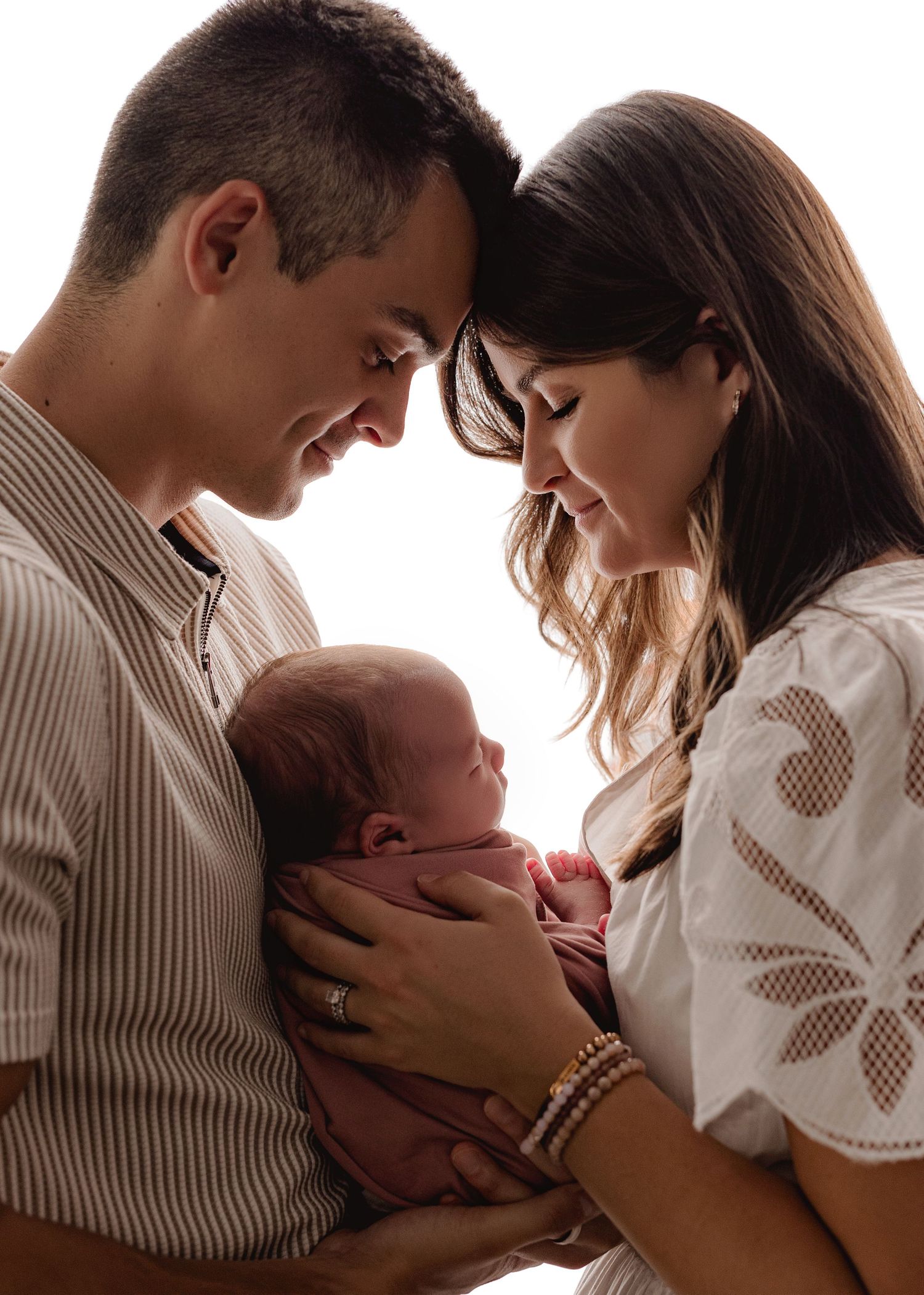 A series of tender moments showing parents cradling and bonding with their newborn baby in a softly lit setting.