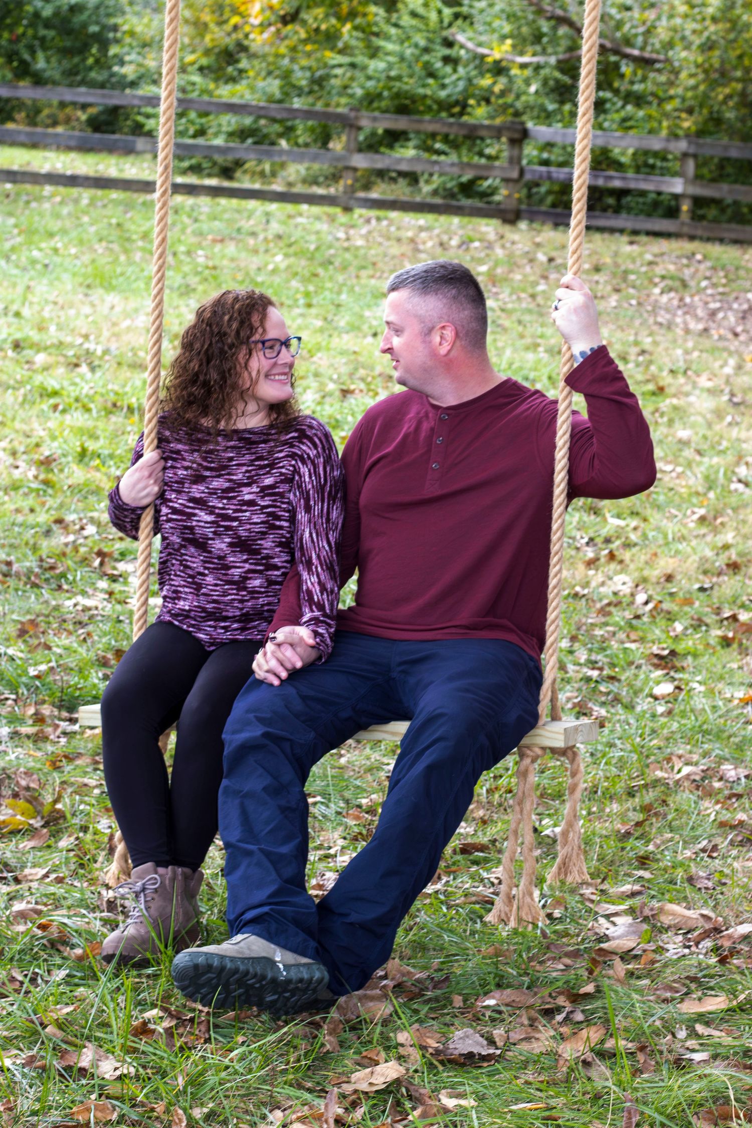 Couple sitting together on outdoor swing in autumn garden setting.