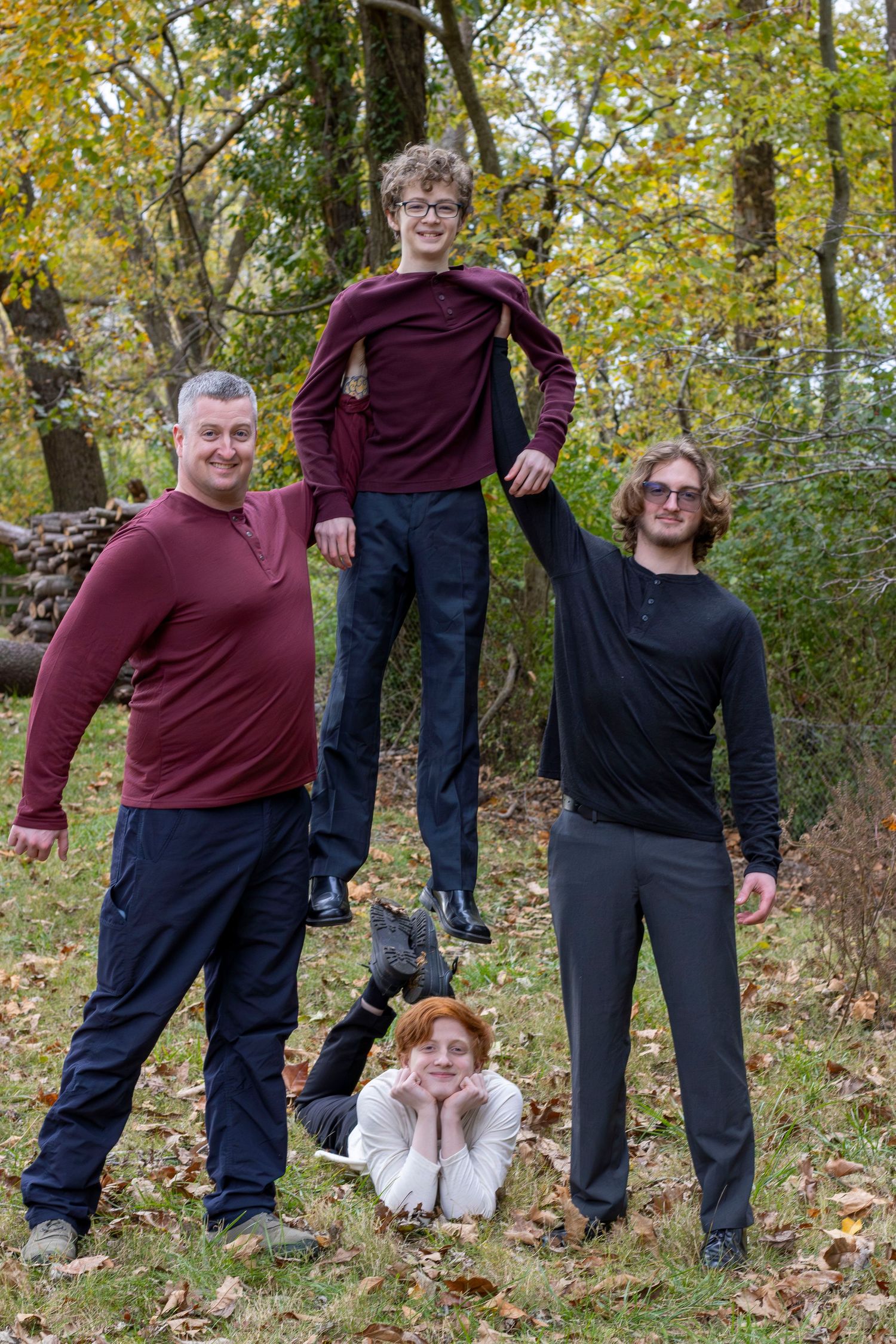 Playful family photo shoot with creative poses among fall leaves.