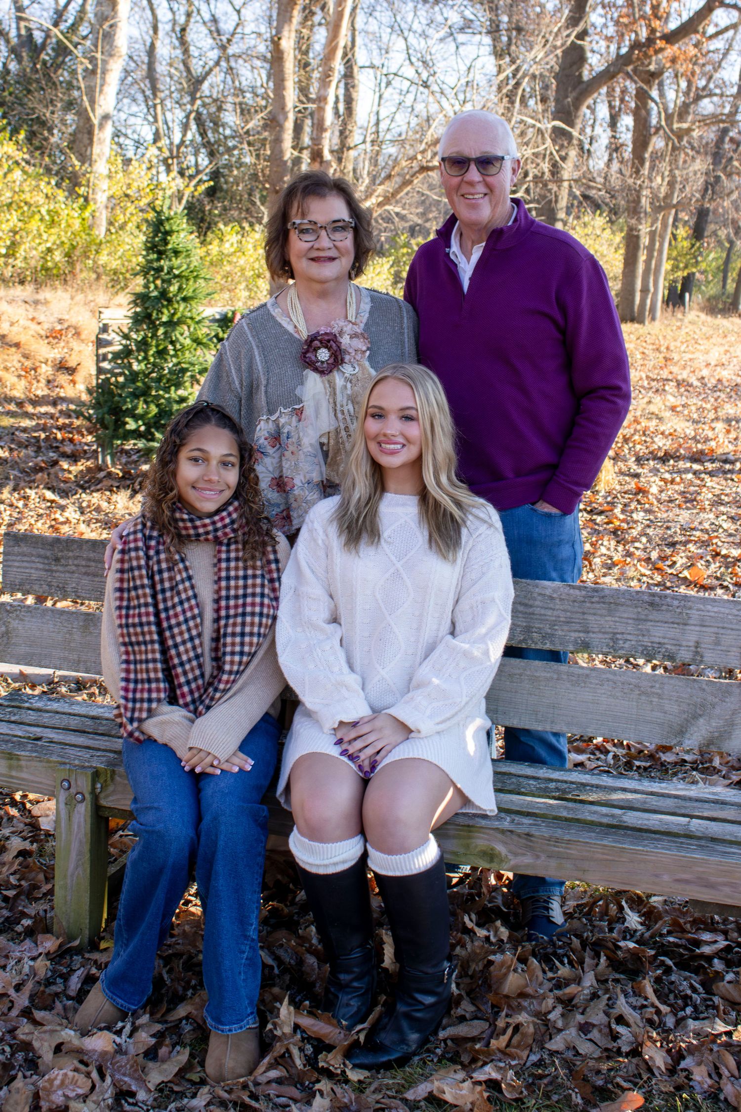 A fall family photo session on a wooden bench surrounded by autumn leaves.