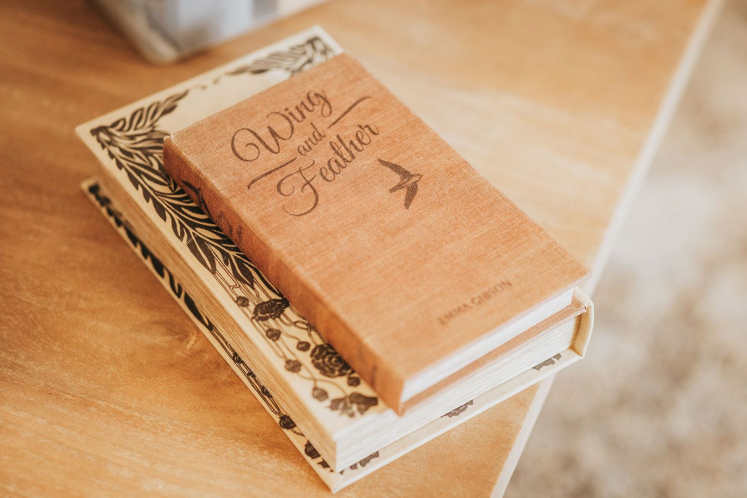 Rustic wooden guest book with decorative floral design displayed on light wooden surface.
