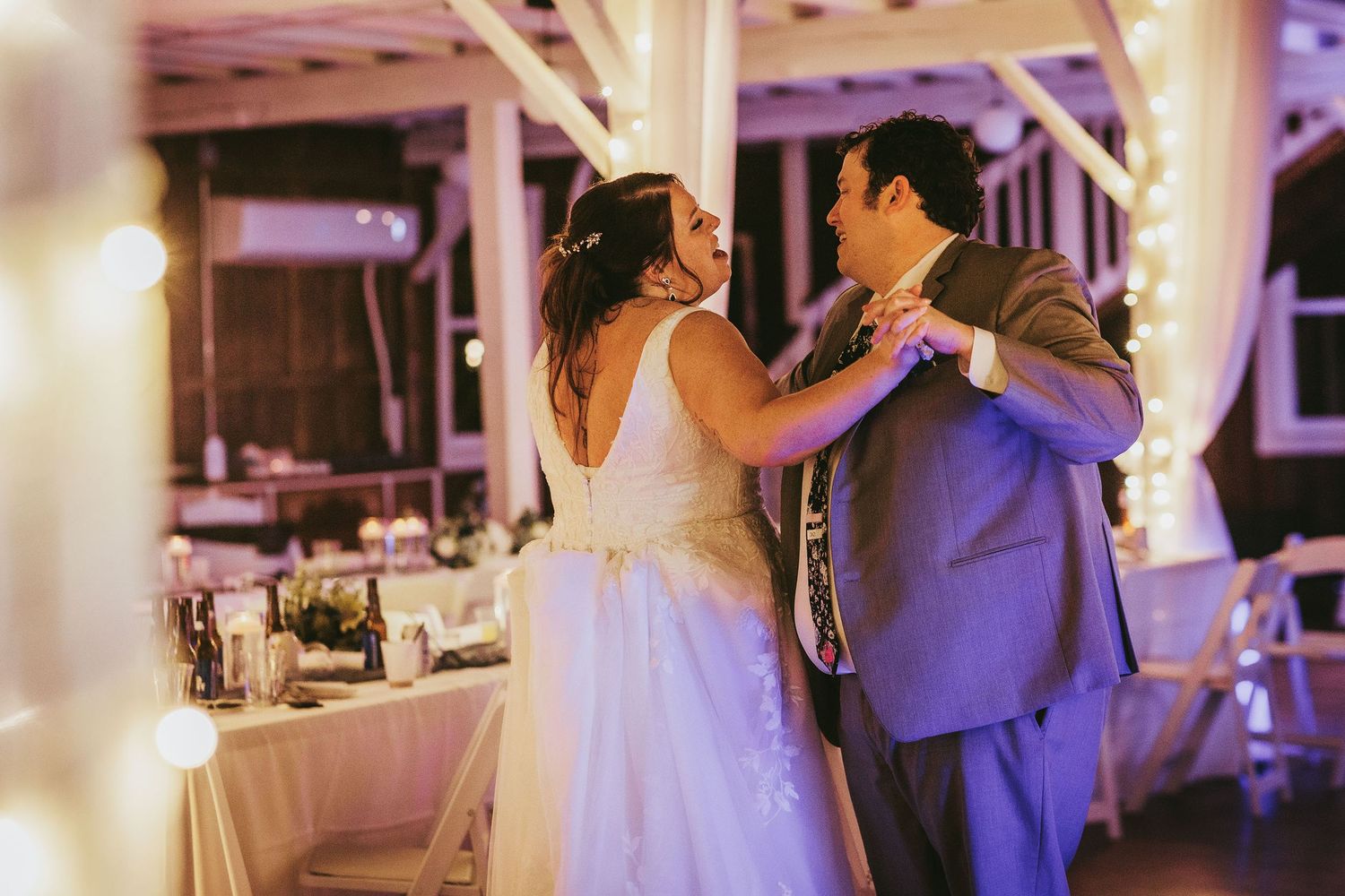 Wedding reception dance floor illuminated with purple lighting and white decor elements.