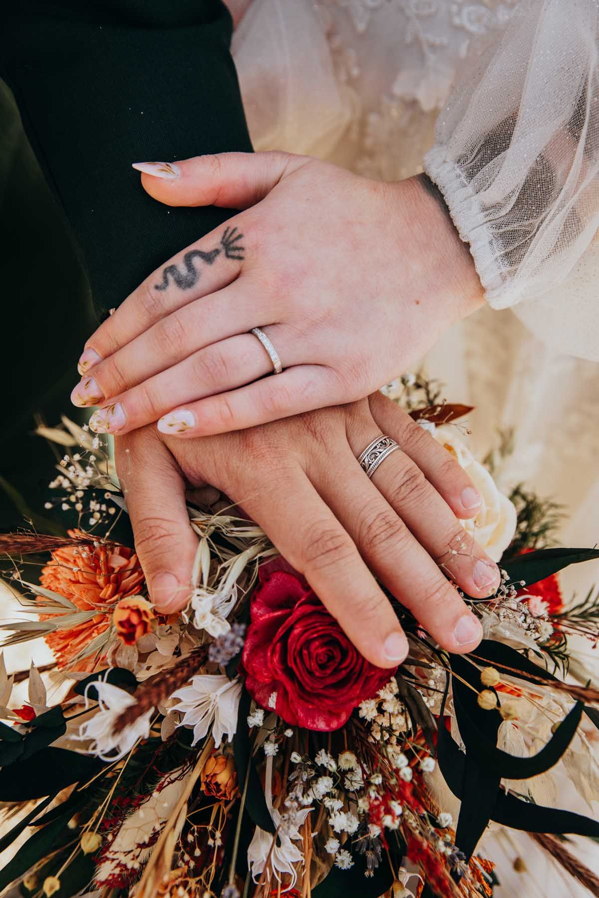 Close-up photos of wedding rings and autumn-themed floral bouquet with red roses and dried flowers.